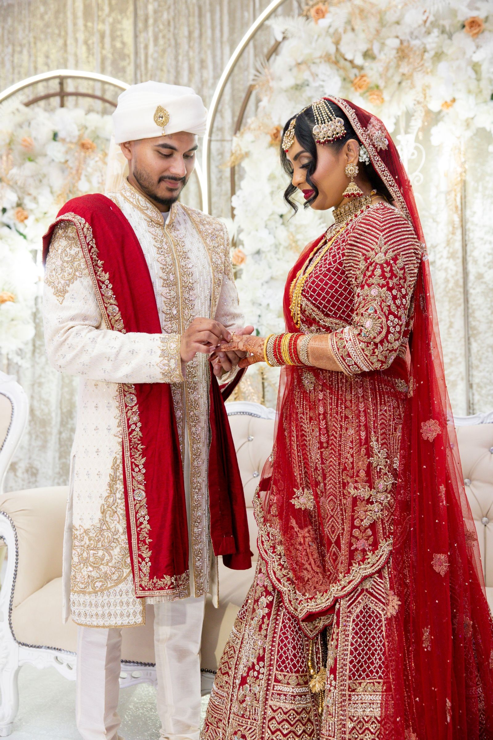Bride and groom facing each other on the stage, she in deep red, he in ivory and red