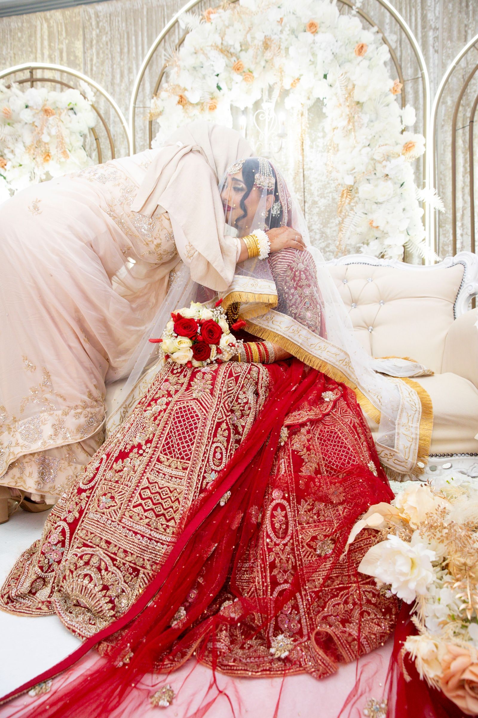 A relative leaning in to kiss the bride's forehead on the stage