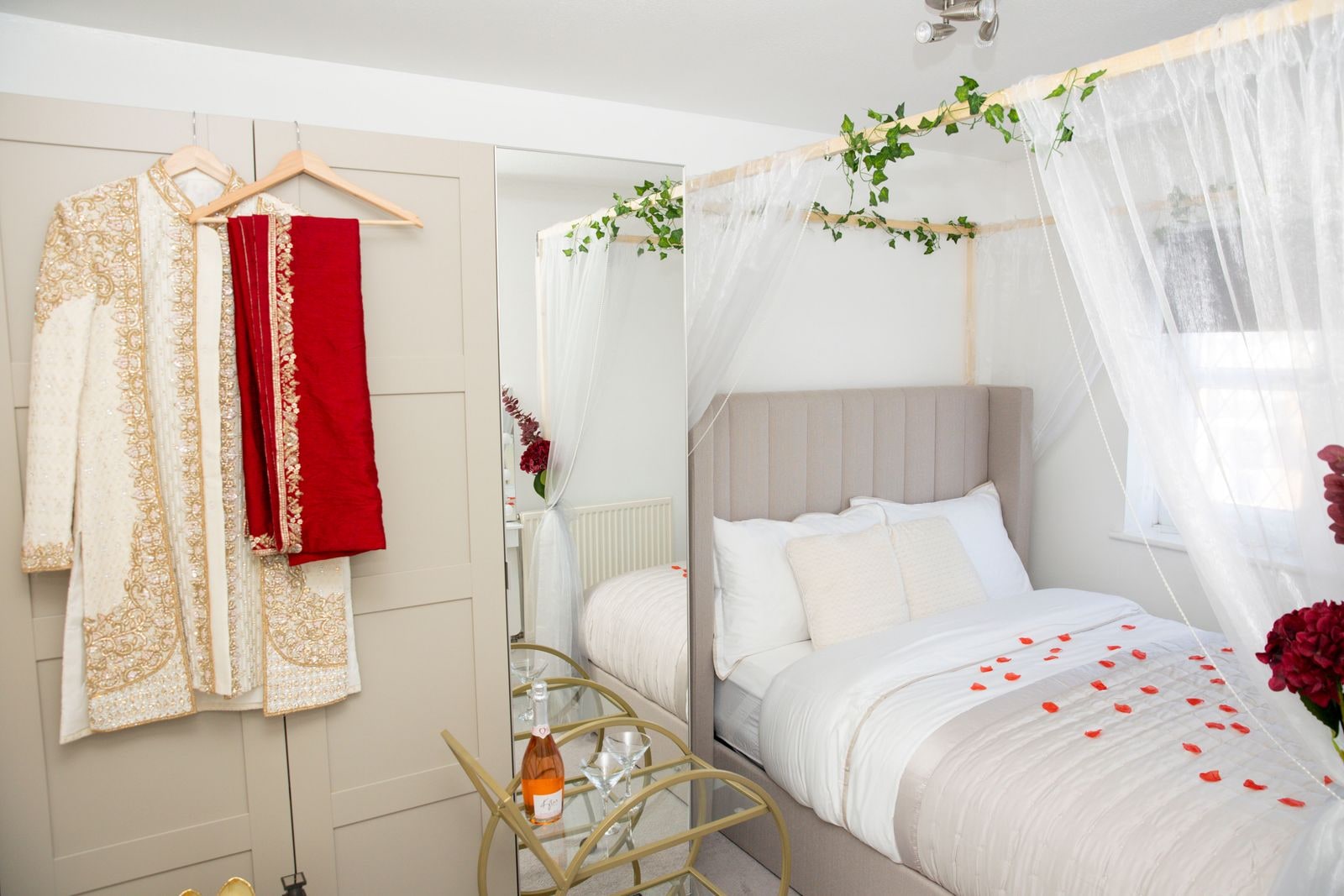 The bridal suite before the wedding, the couple's outfits hung ready and petals on the bed