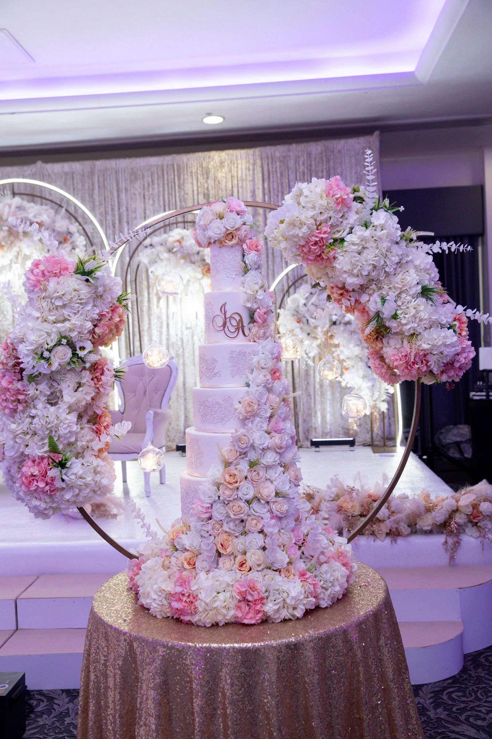 The wedding cake on a gold cloth inside a heart of pink and white flowers