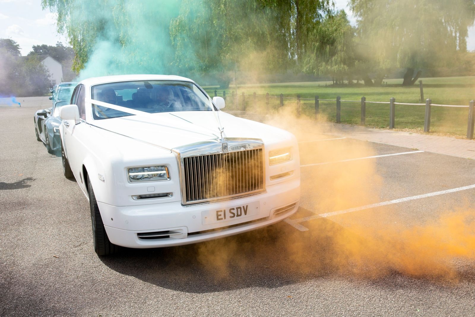 White Rolls-Royce Phantom with orange and green smoke drifting across it
