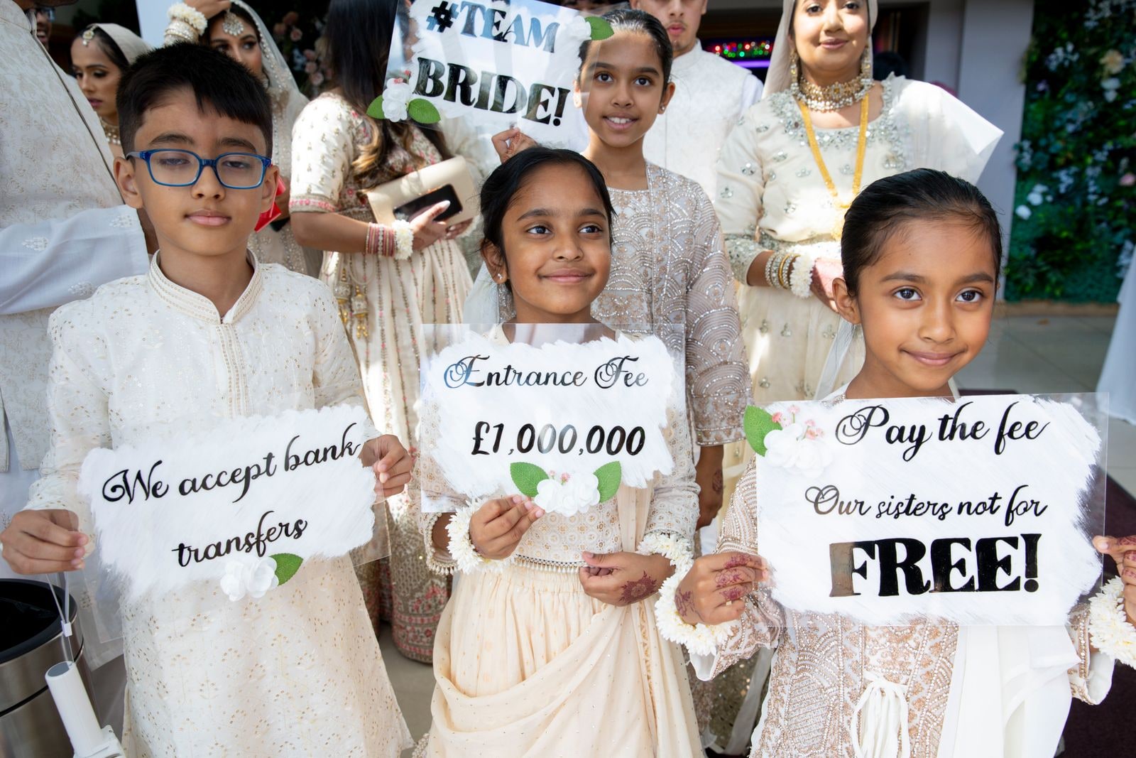 Children holding handwritten signs reading 'Entrance fee, one million pounds' at the door