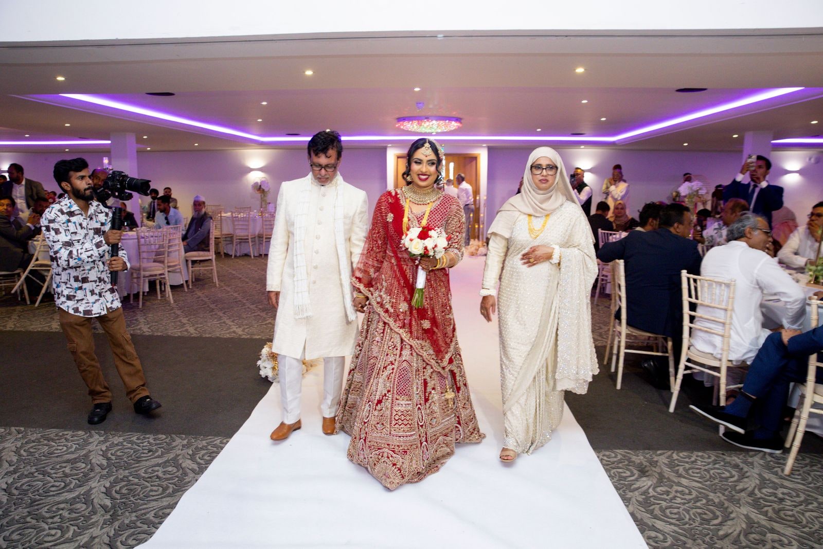 Bride walked down the aisle by her parents as guests turn to watch