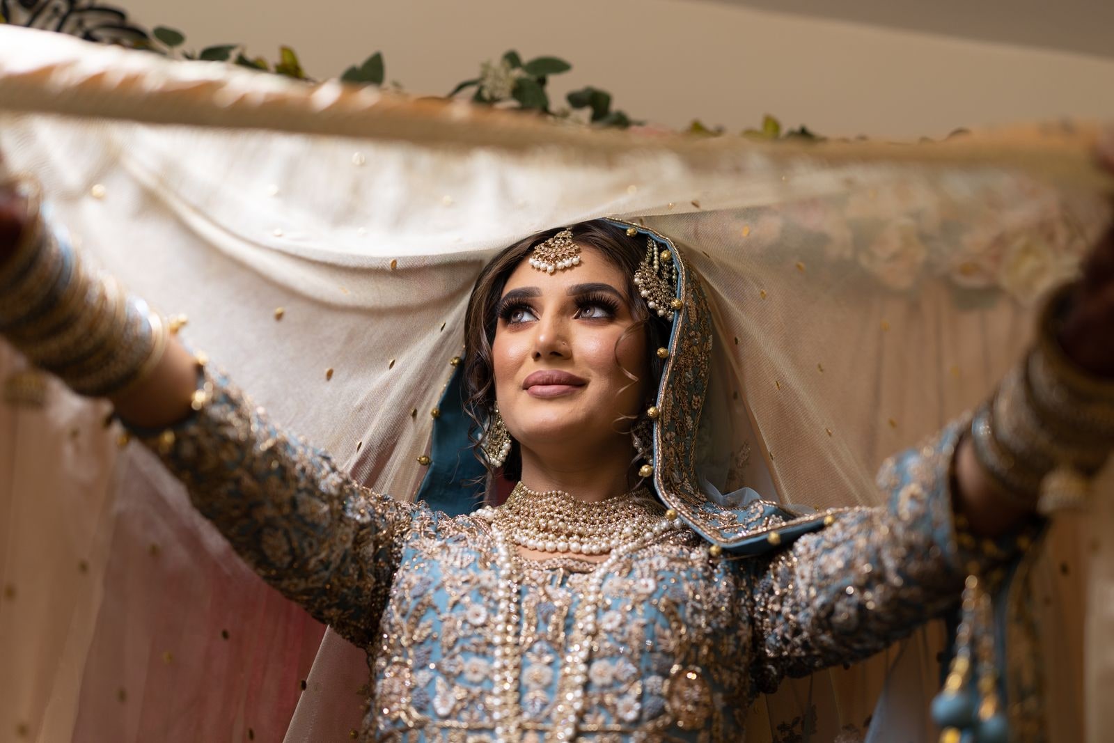 Bride with her arms outstretched beneath a canopy, looking up