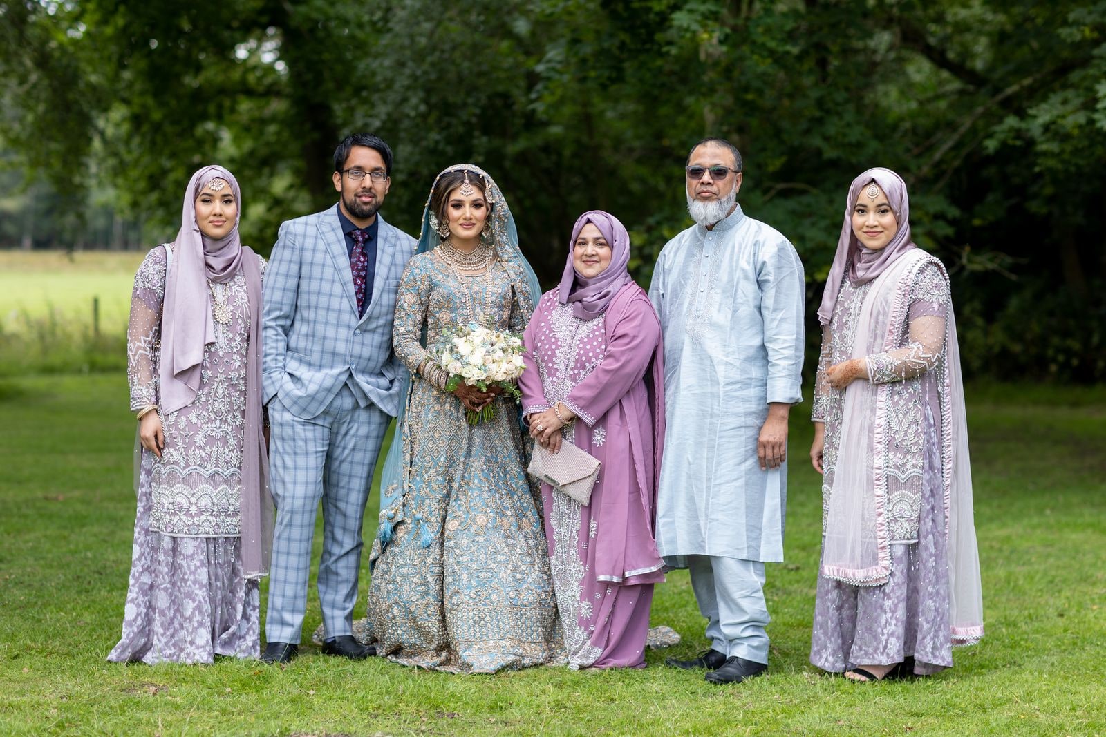 The bride's family gathered around her on the grass for a group portrait