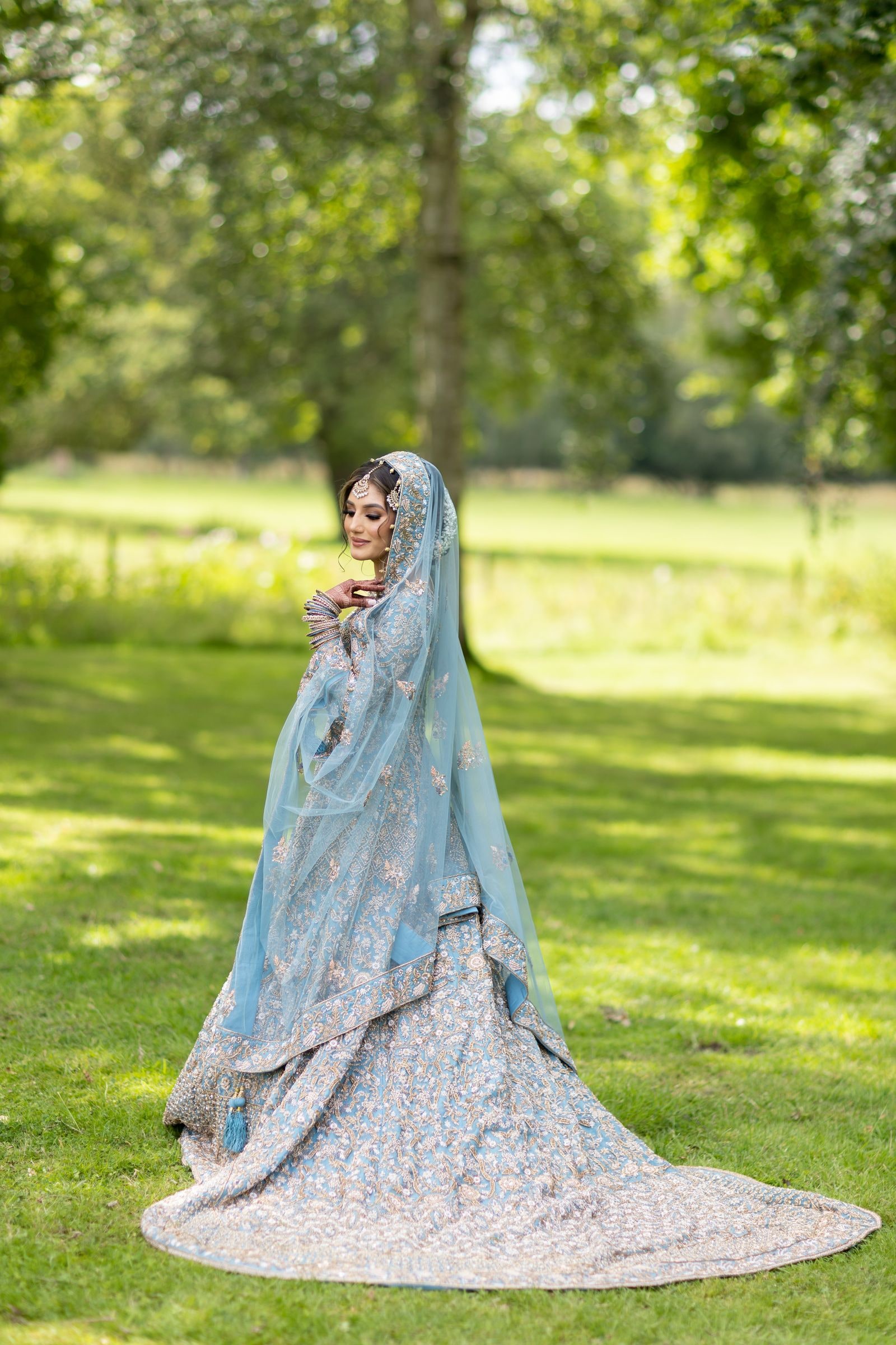 Bride turning on the grass, her pale blue train sweeping around her