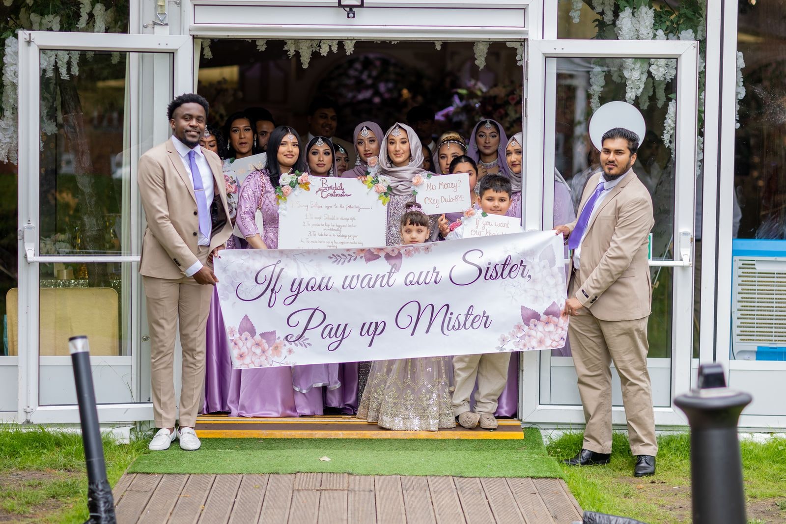 The bride's family blocking the doorway with a banner reading 'If you want our sister, pay up mister'