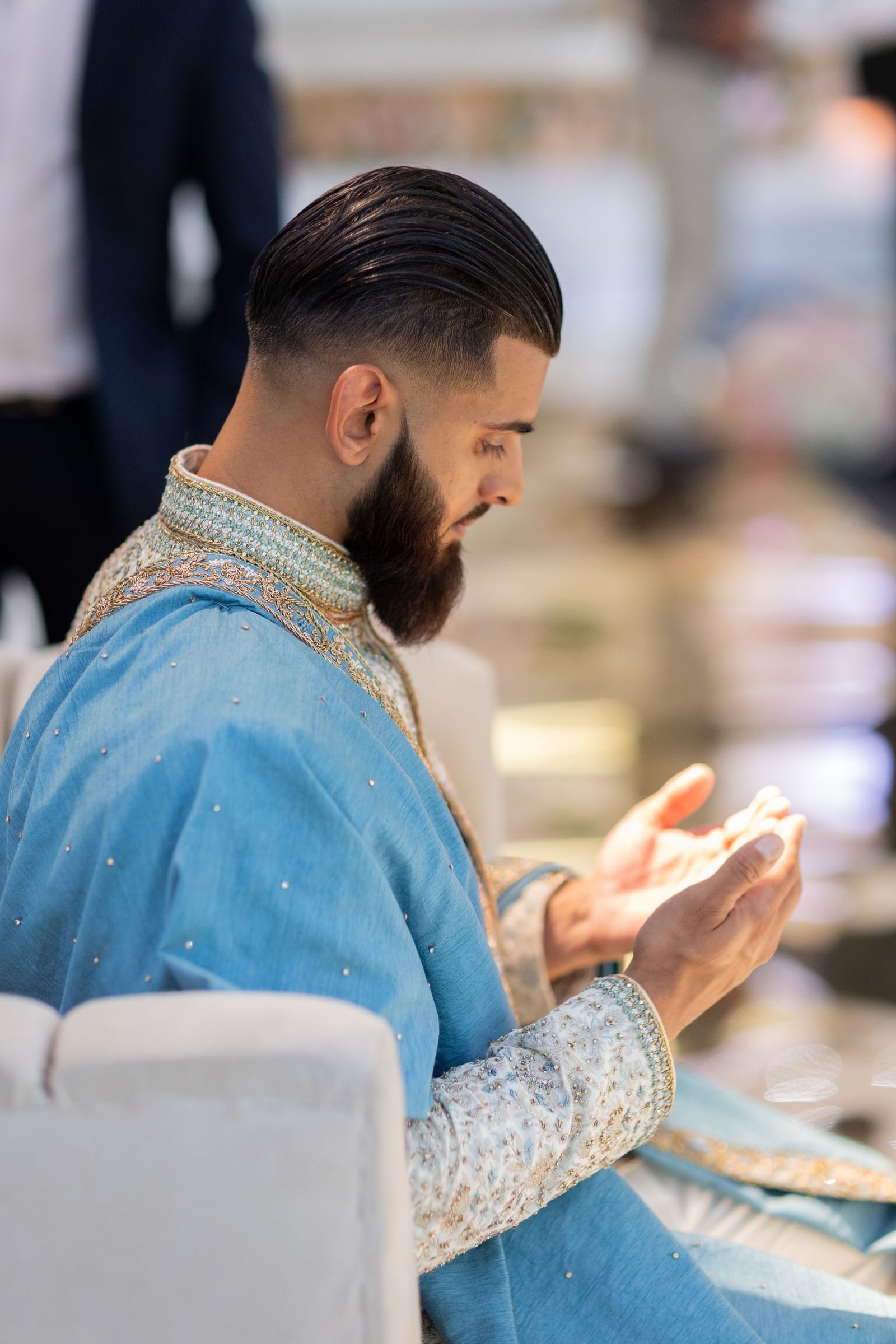 Groom in profile with his hands raised in prayer