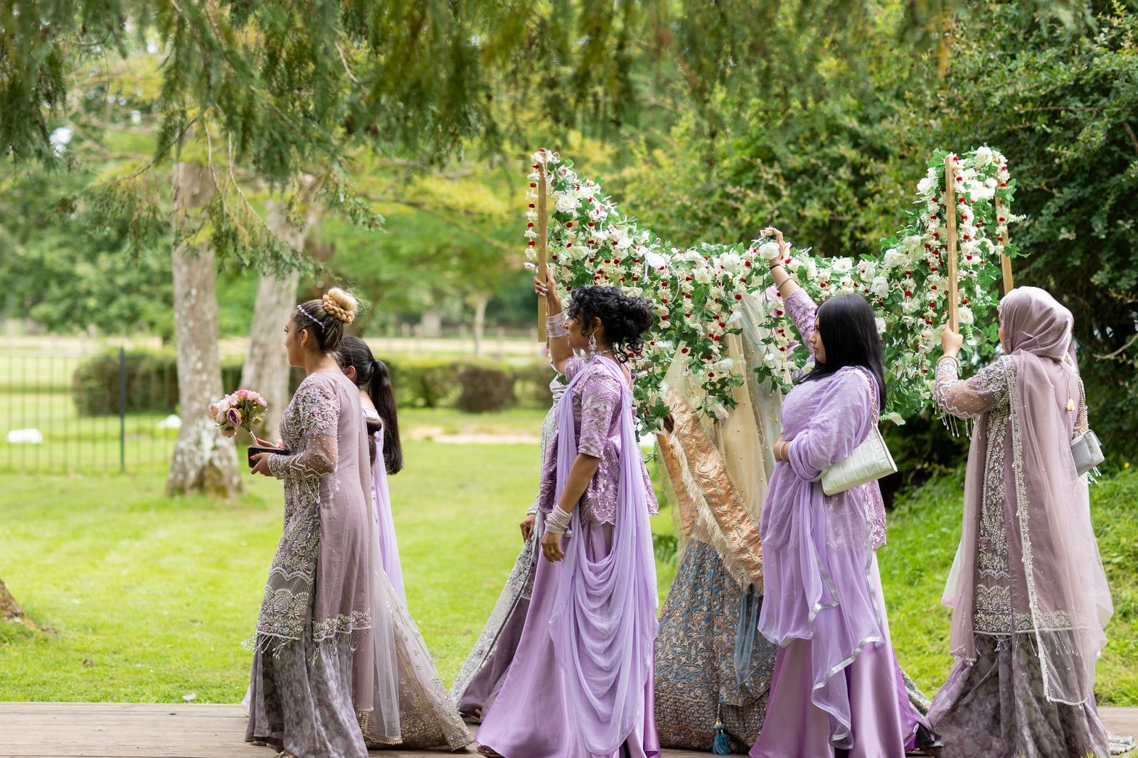 The canopy carried over the bride as her party walks her across the lawn