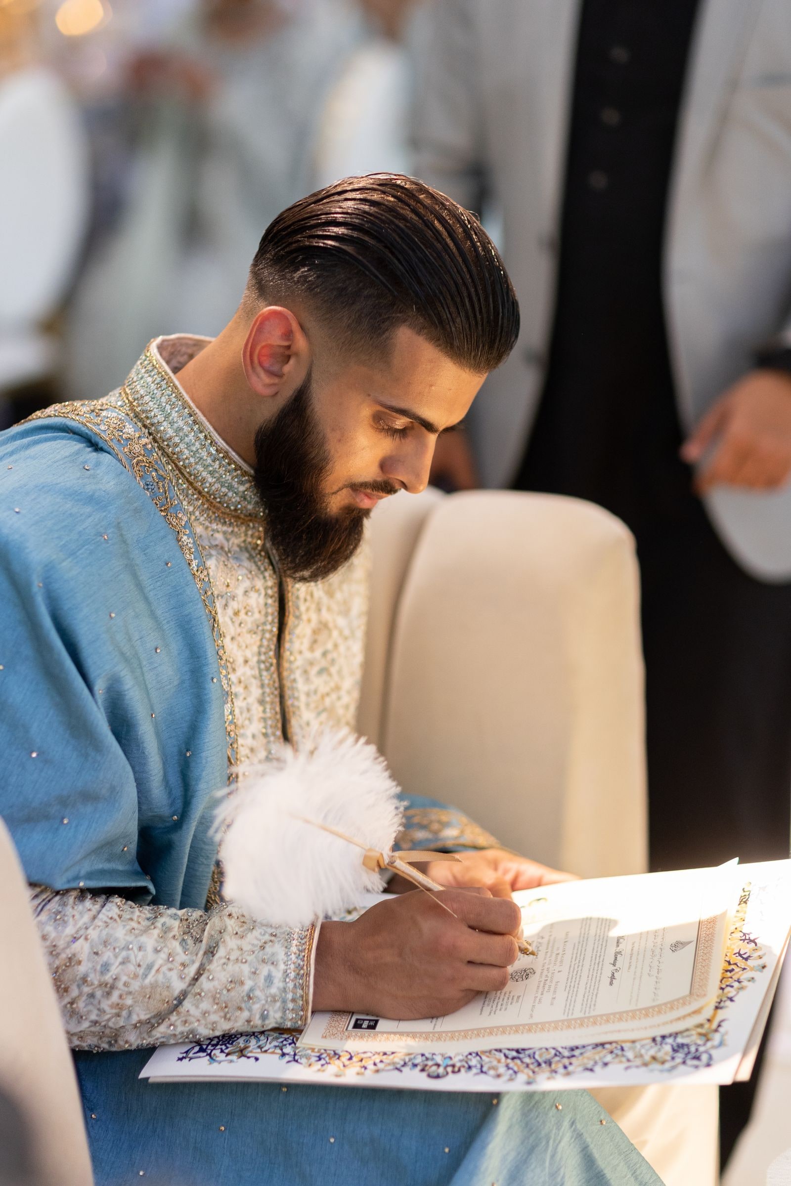 Groom signing the nikkah papers with a feather pen