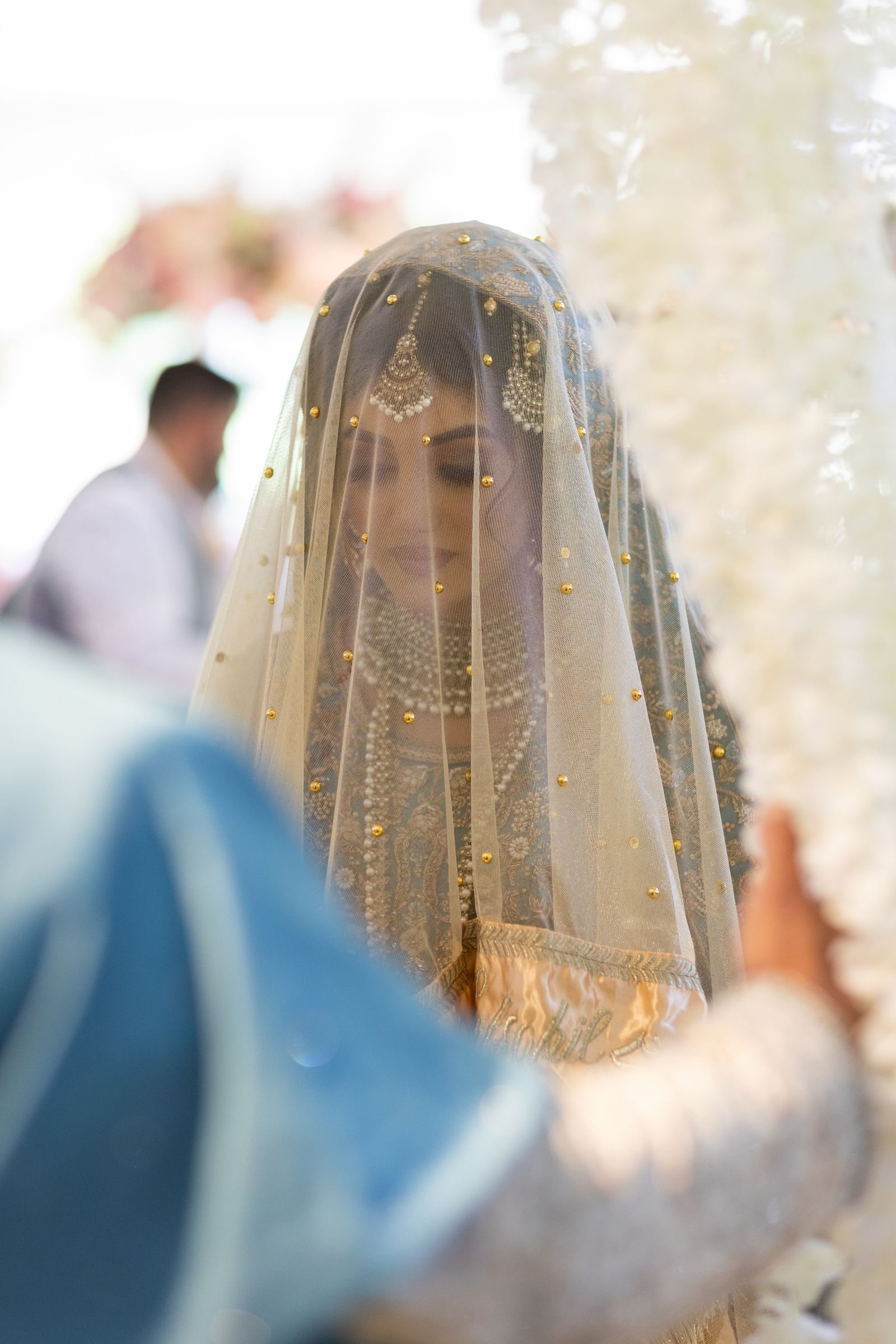 Bride veiled in gold as the groom reaches towards her