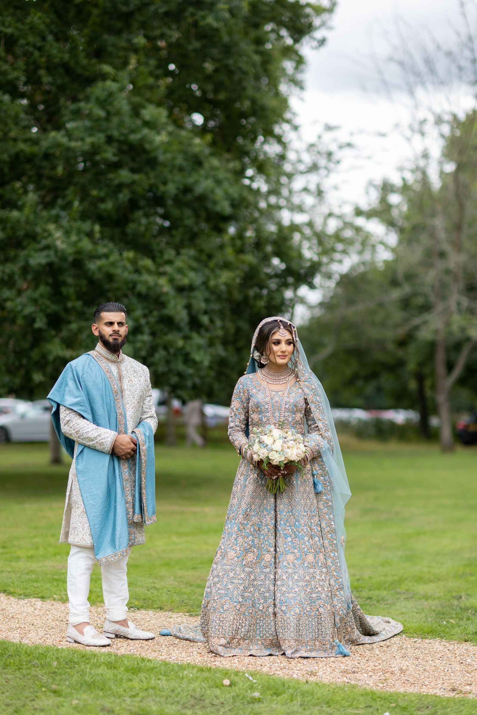 Couple standing on the gravel path in the parkland at Warbrook House