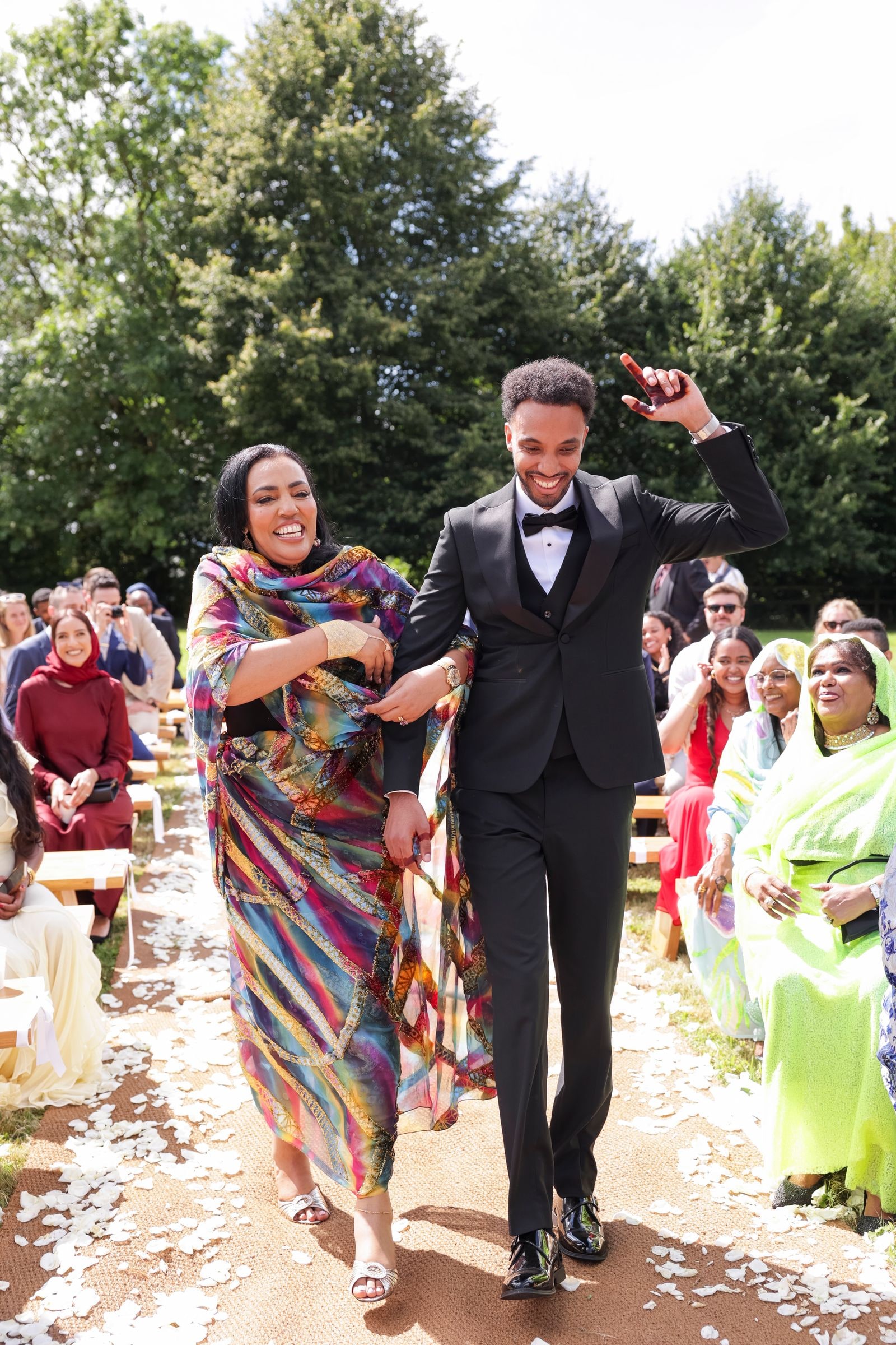 Groom walking his mother back down the aisle, guests seated on both sides