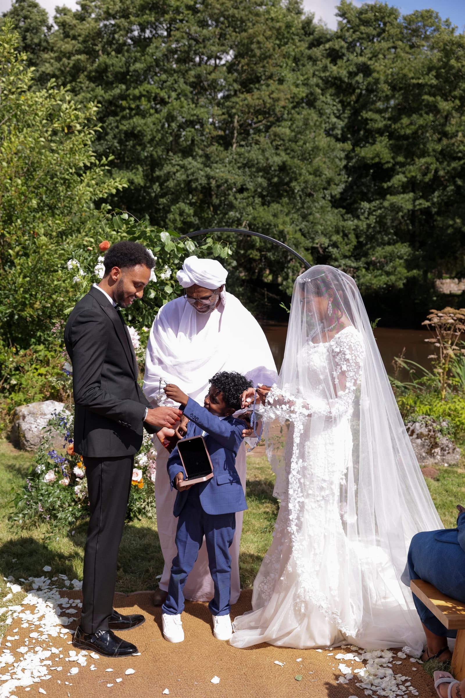The couple at the outdoor ceremony, the celebrant reading between them