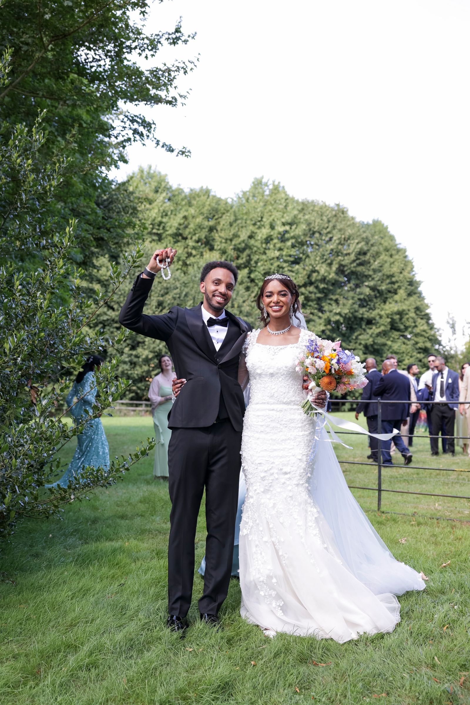 Bride and groom on the lawn, he raising his hand in celebration