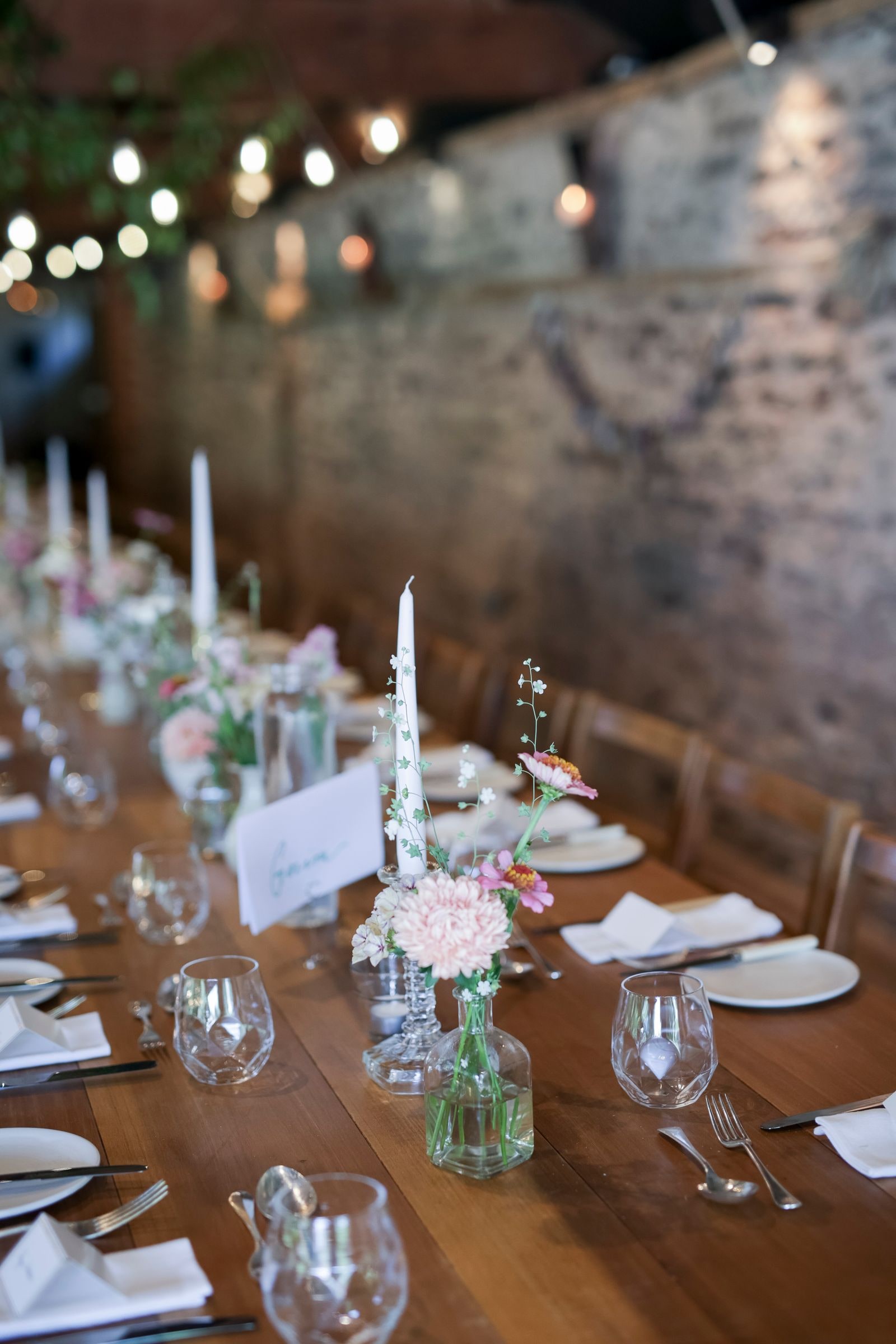Close view of the table setting, candles and small posies along the wood