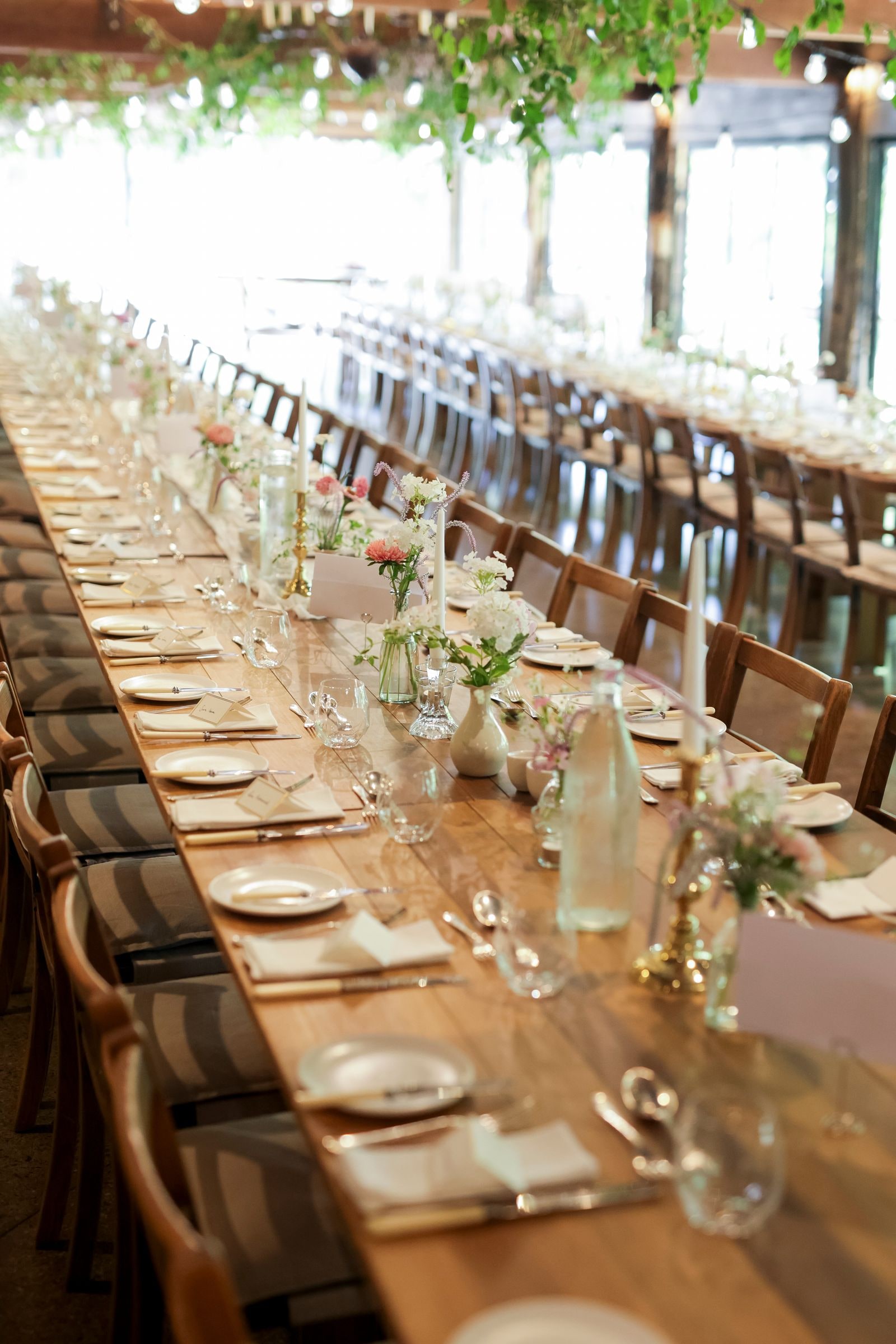The long dinner table laid with candles and posies down its length