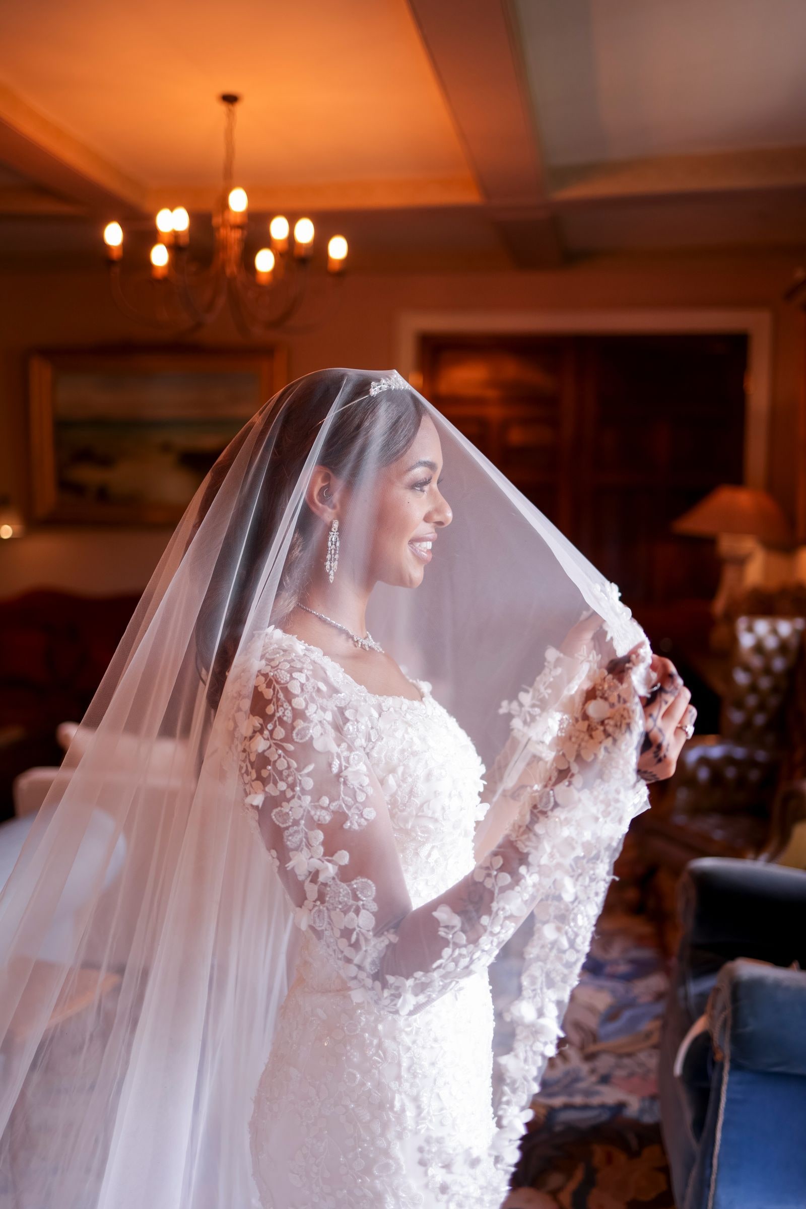 Bride in a panelled room, her veil lifted, beneath a chandelier