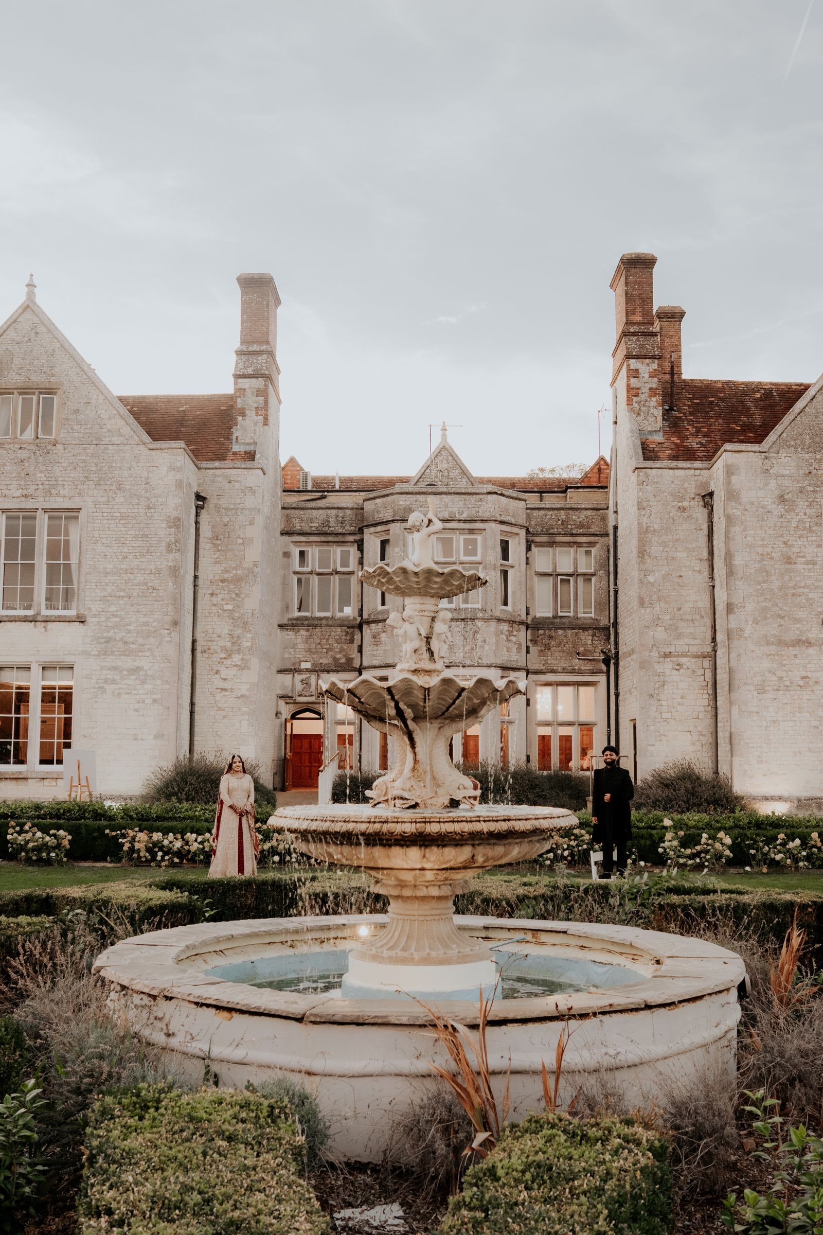 The garden fountain with the gabled stone house rising behind it