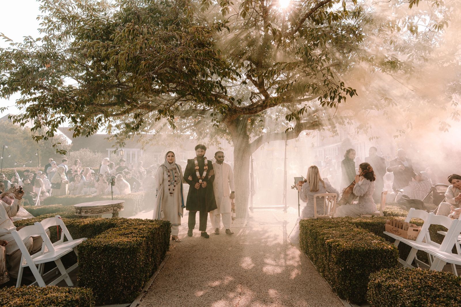 Bride and groom walking down the outdoor aisle through drifting smoke