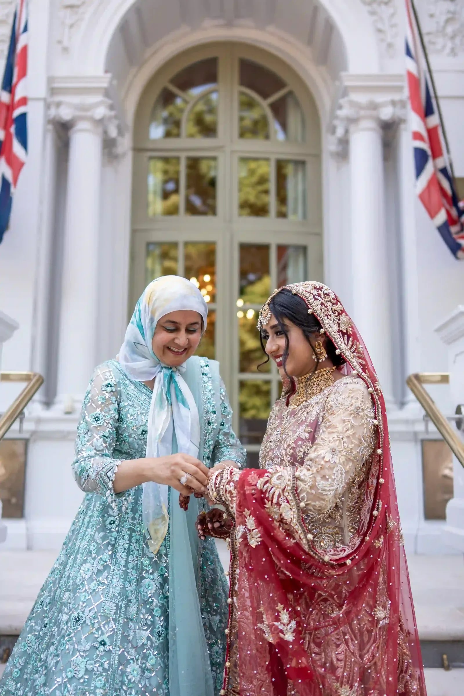 A woman in pale blue holding the bride's hand outside the hotel