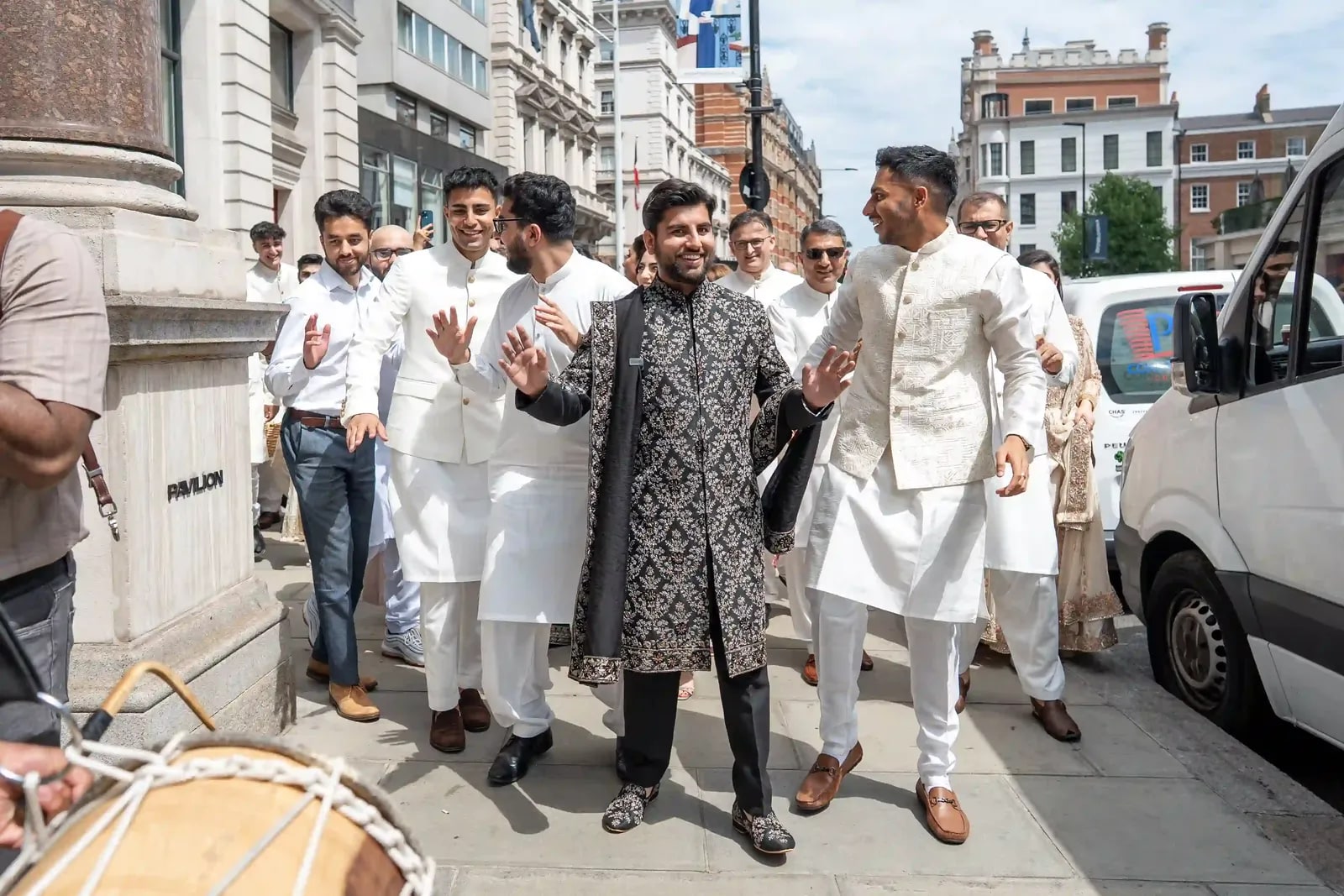 Groom walking the London street with his friends, a dhol player leading them