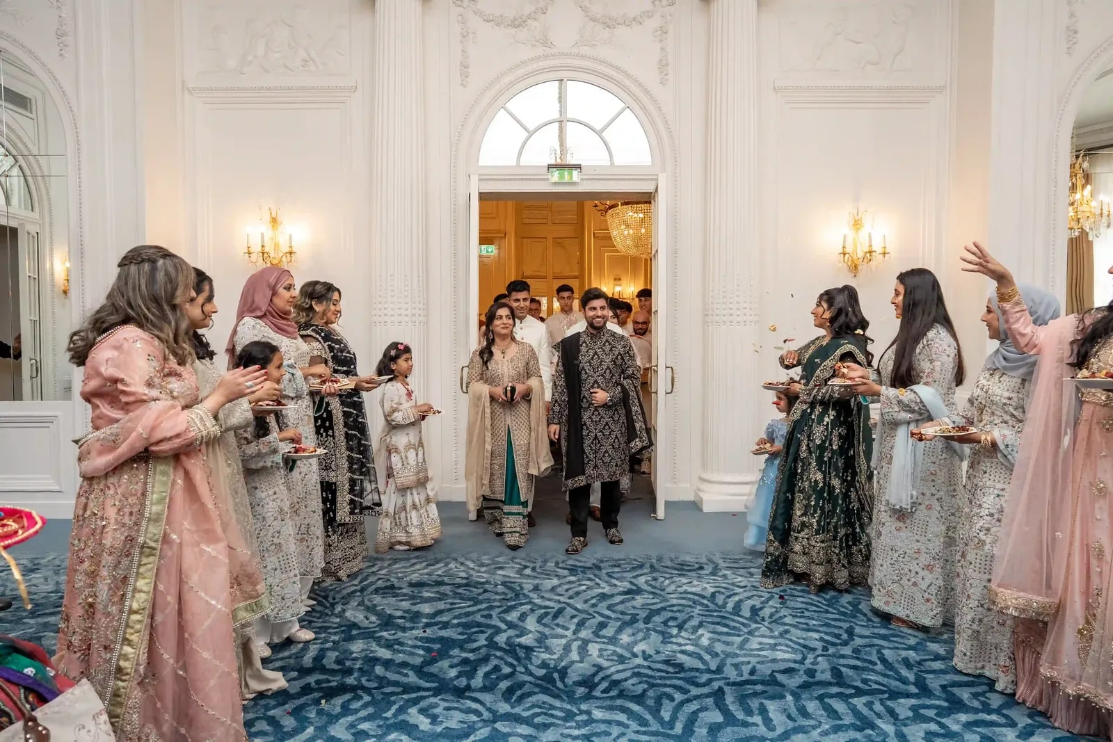 Bride and groom walking in through the doorway as guests throw petals