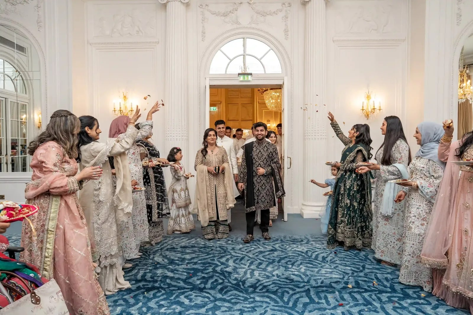 Guests scattering petals over the couple as they come into the ballroom