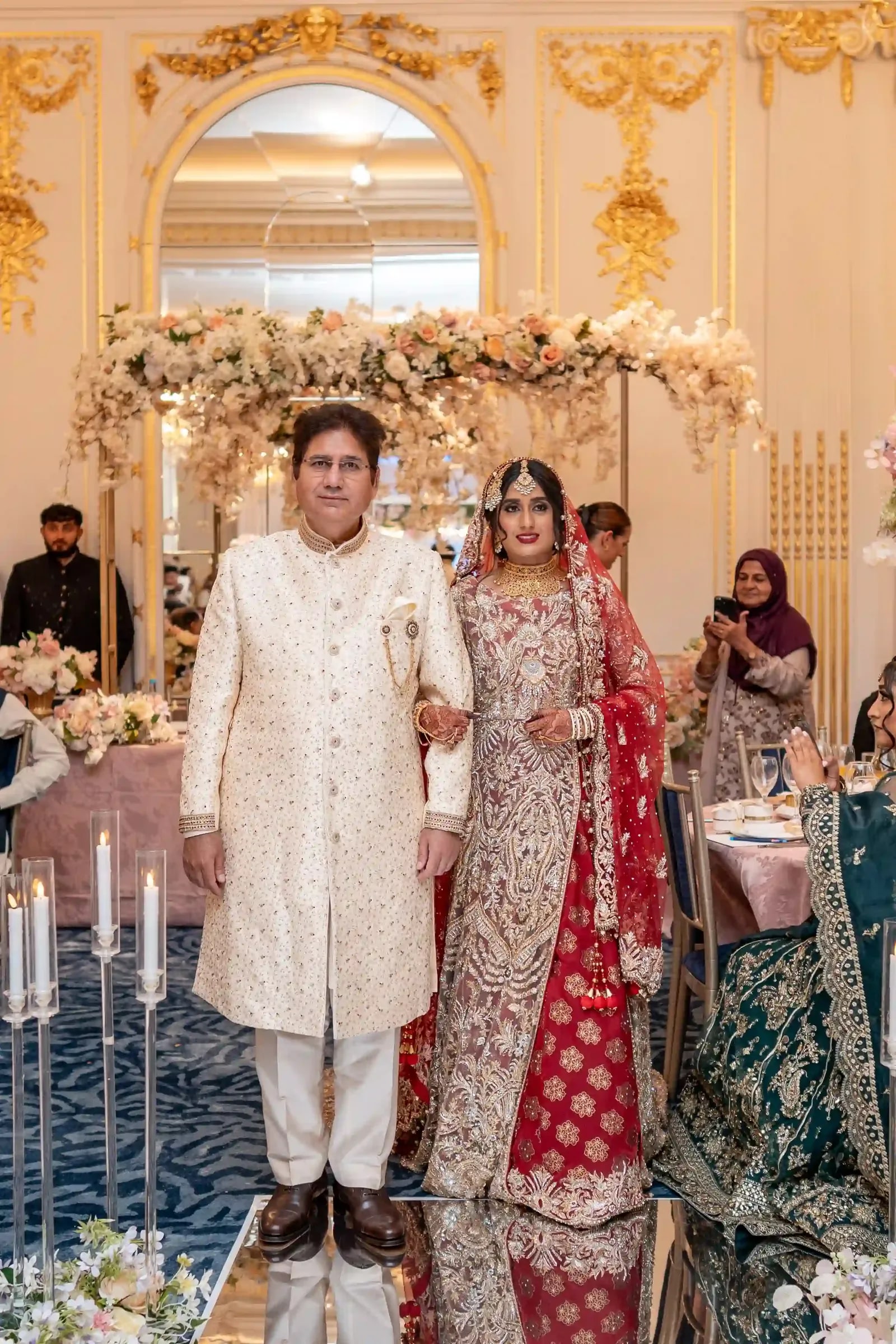 The bride's father walking her in beneath a canopy of pale flowers