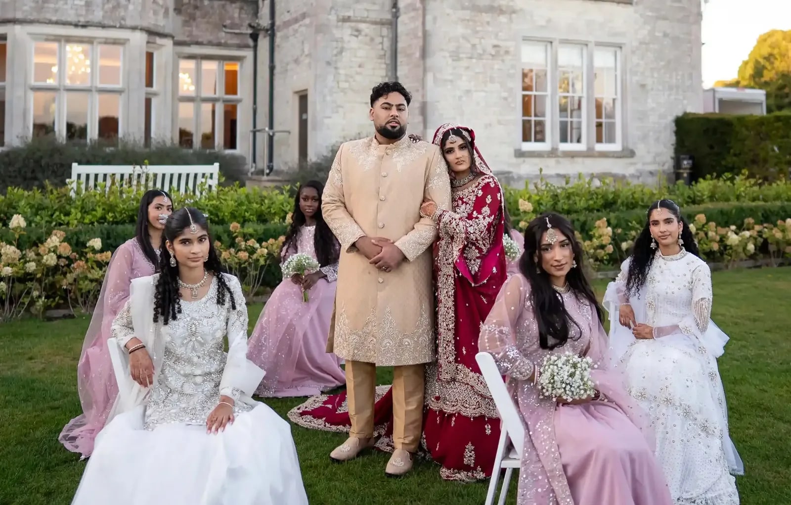 Groom standing with the bride and her party on the lawn in front of the house