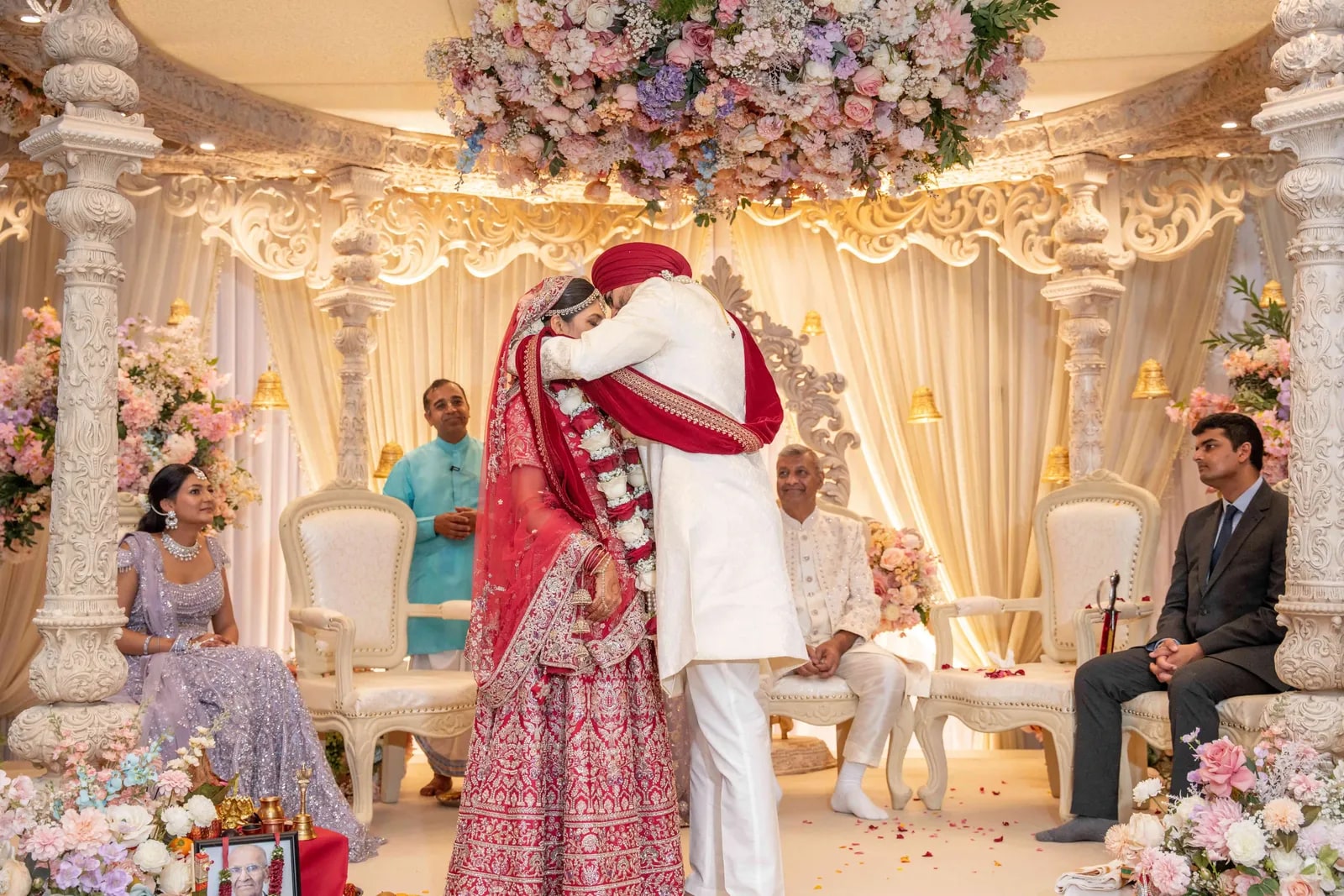 Bride and groom exchanging garlands beneath the pastel flowered canopy