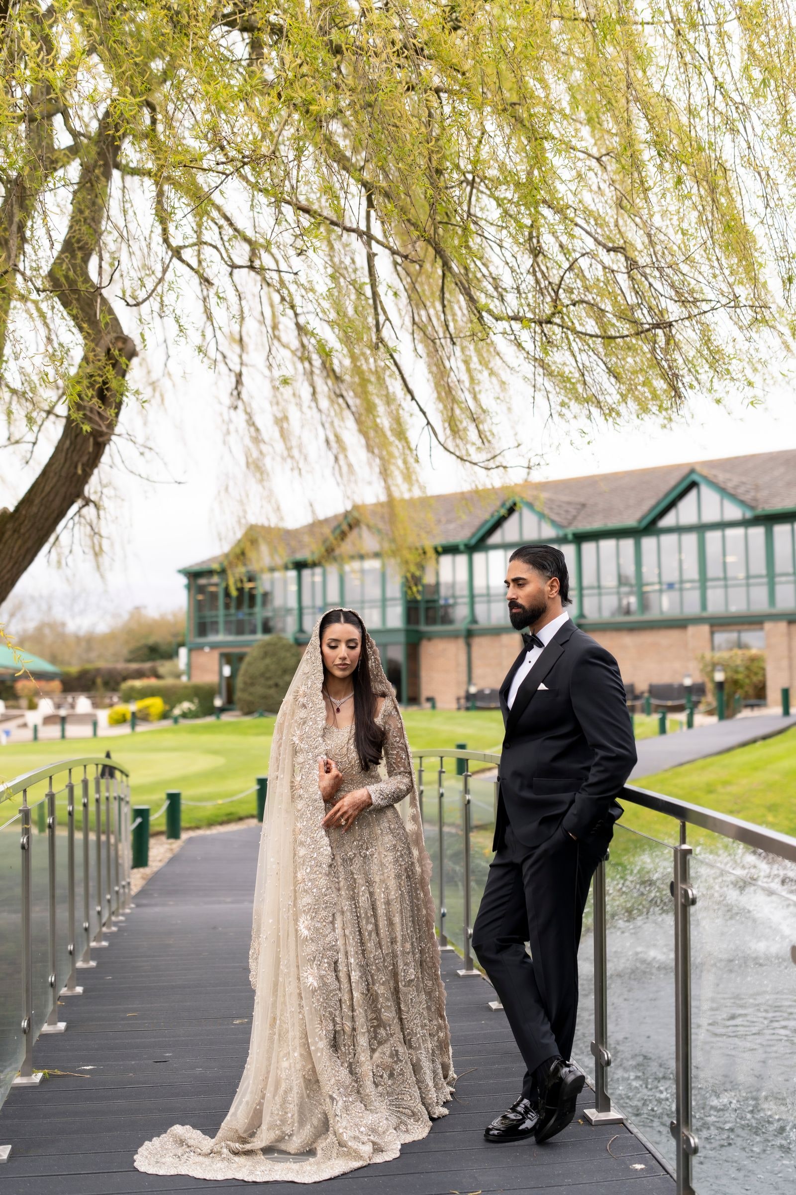 Couple on the boardwalk under willow branches, her long veil trailing