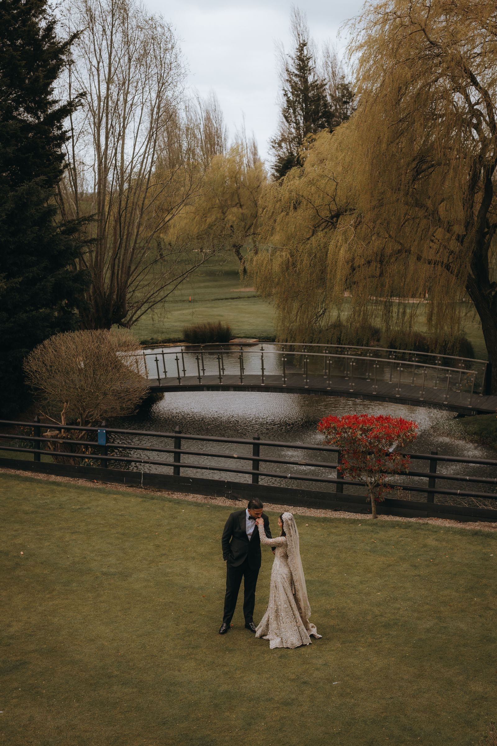 Groom dipping his bride on the lawn by the lake