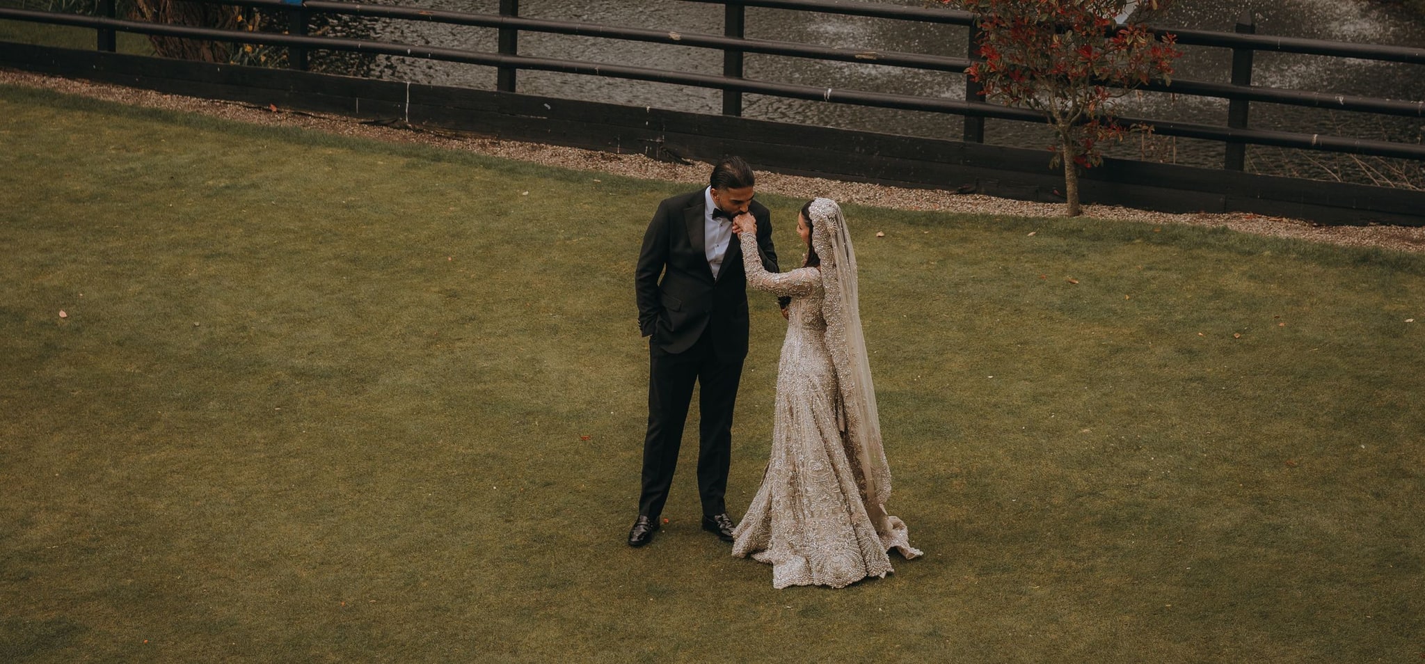 Groom dipping his bride on the lawn by the lake