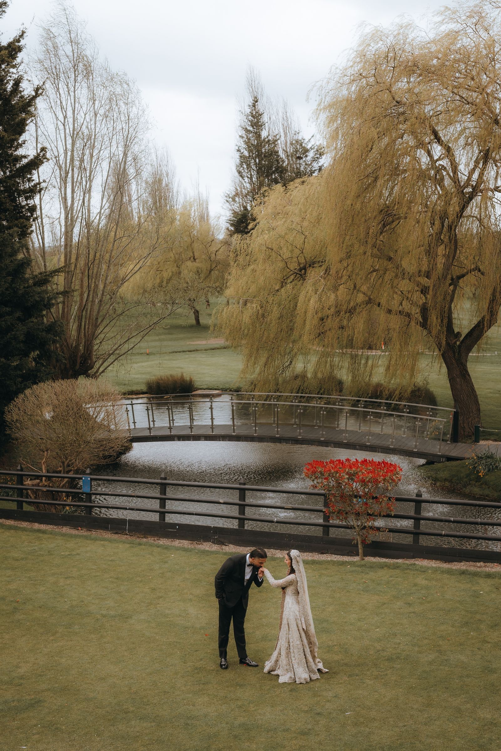 Couple dancing on the grass by the water, willows around them