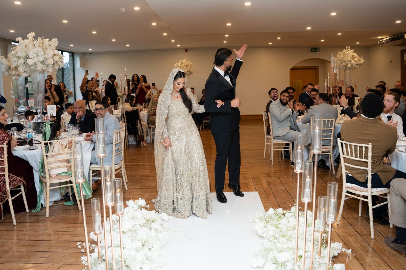 Bride and groom walking the white aisle into the reception, guests at their tables