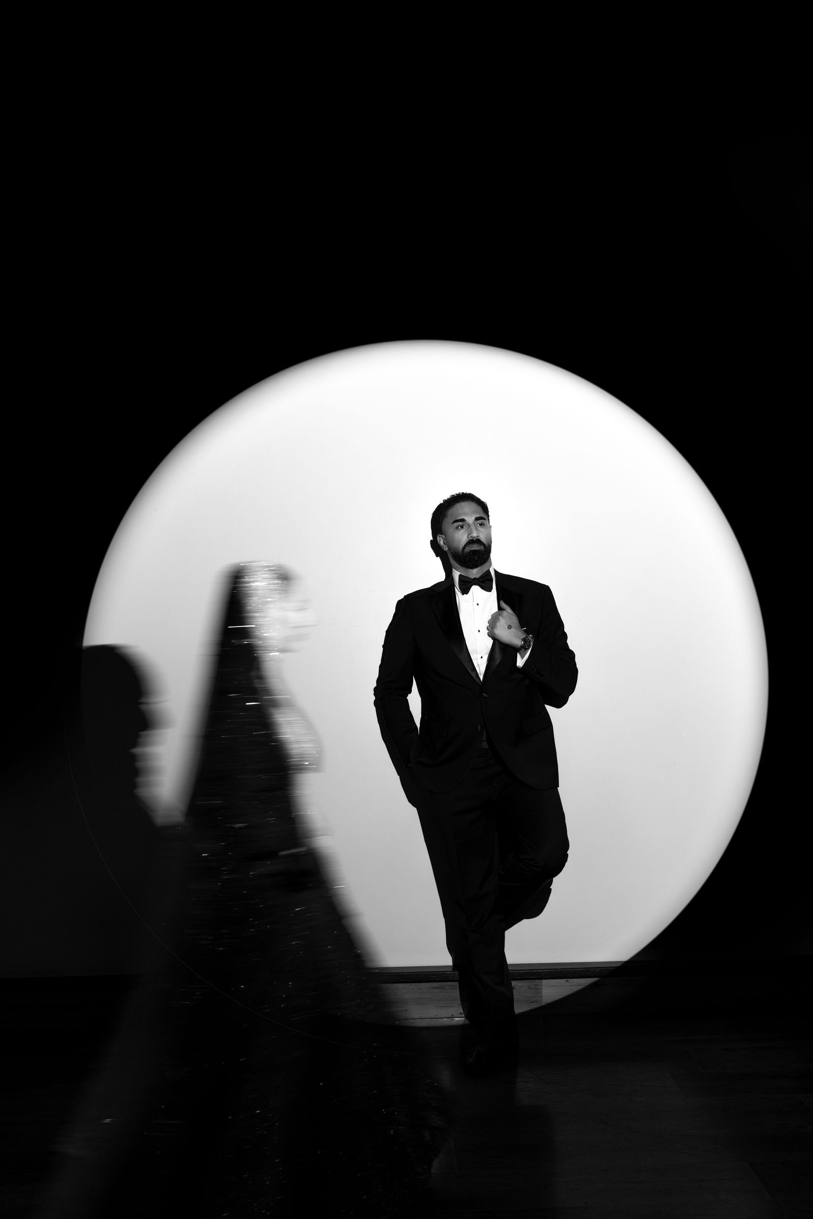 Groom walking into a circle of white light, in black and white