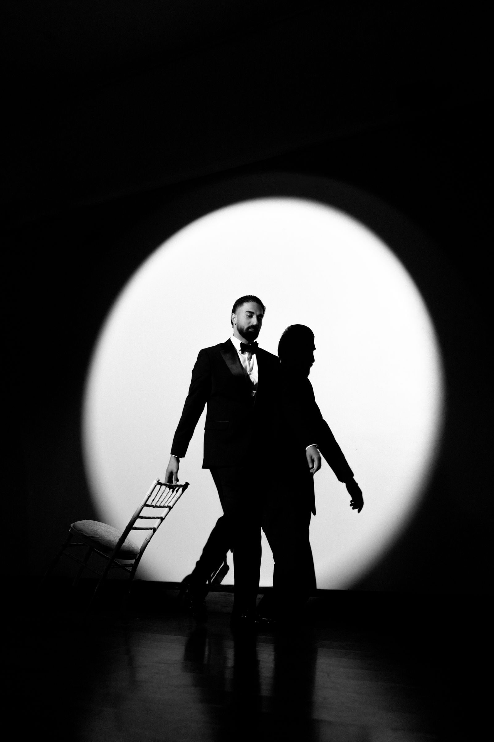 Bride and groom silhouetted in a circle of light, in black and white