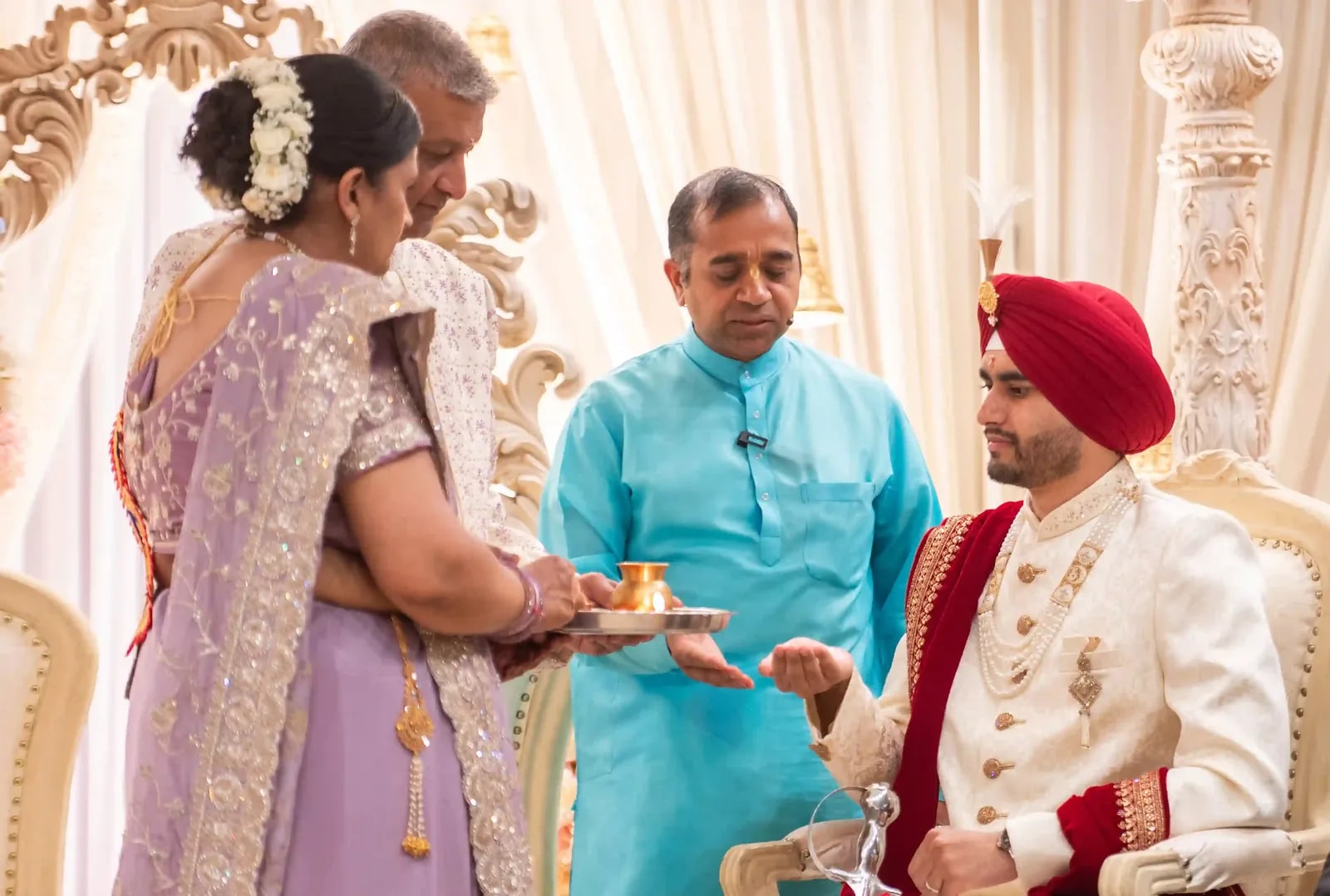 The bride's parents offering a tray to the seated groom during the ceremony