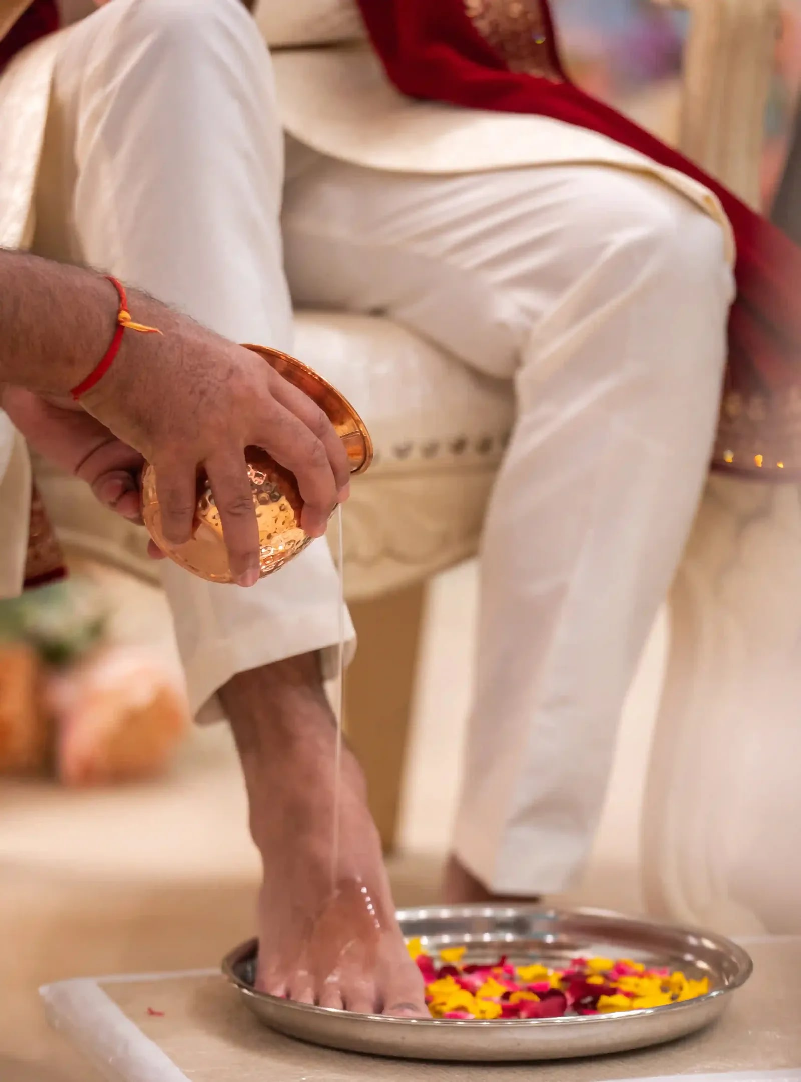 Water poured over the groom's foot into a dish of petals during the pad puja