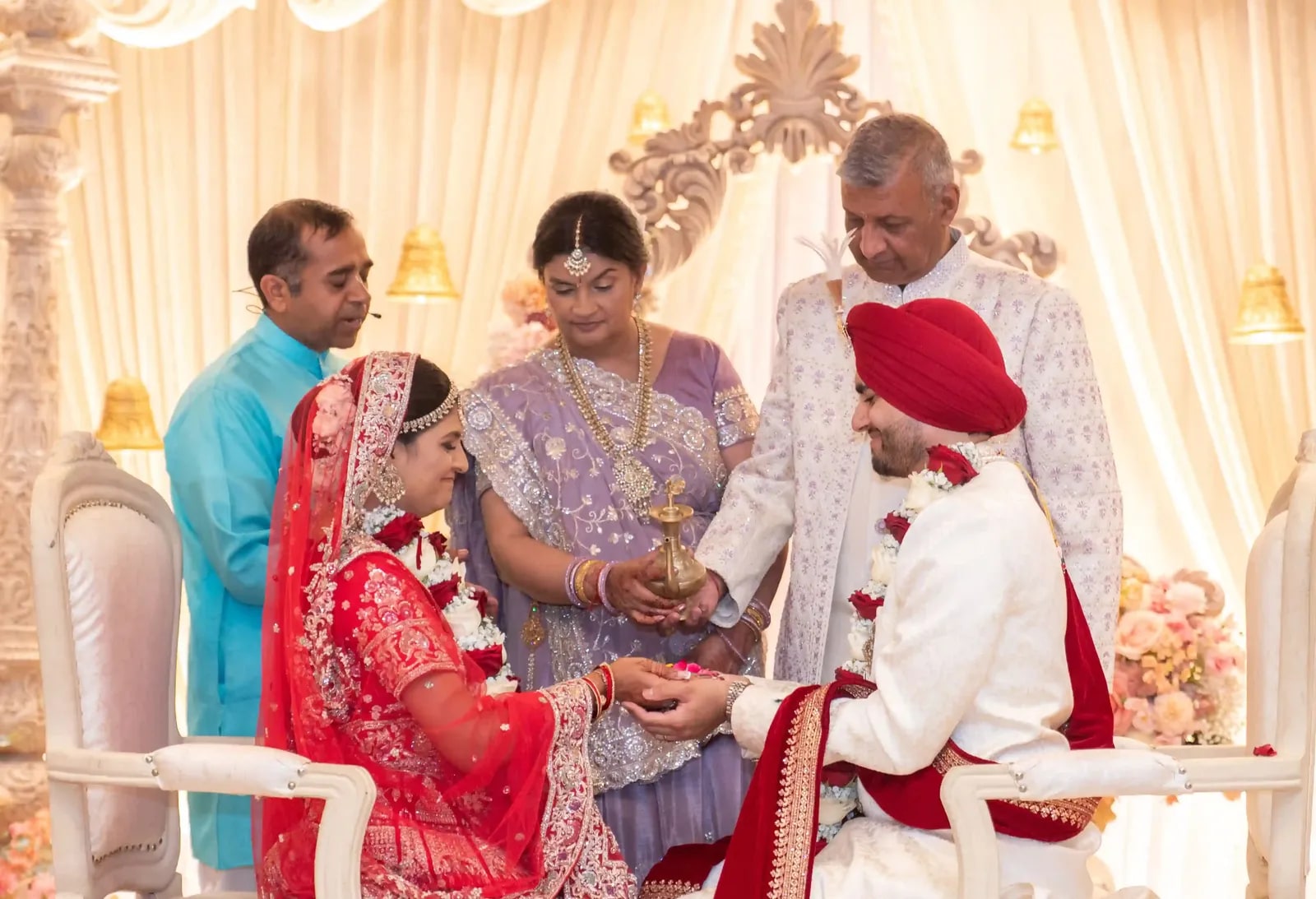 The bride's parents standing over the seated couple during the kanyadaan