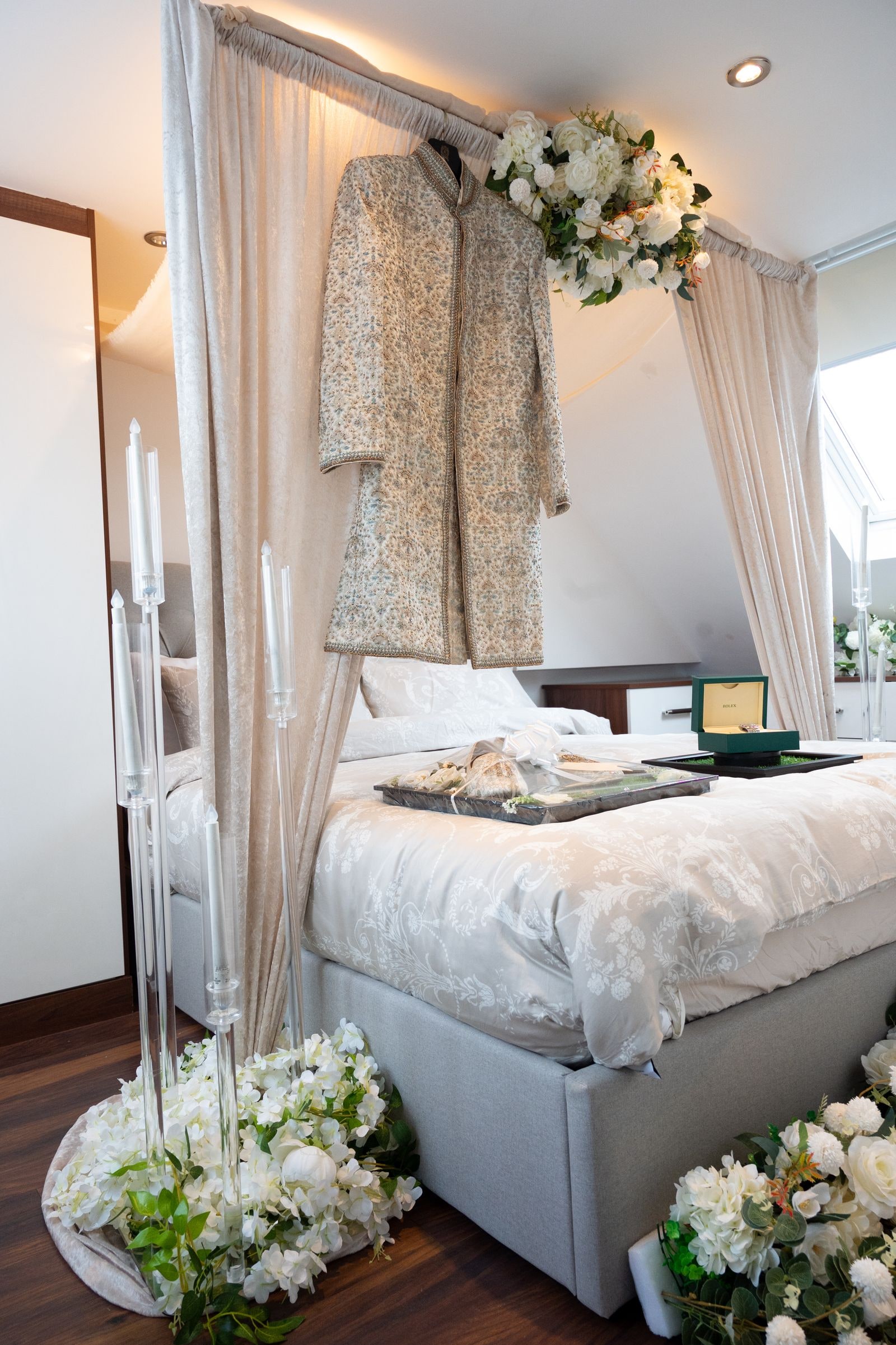 The groom's sherwani hanging in the bridal suite, flowers along the foot of the bed