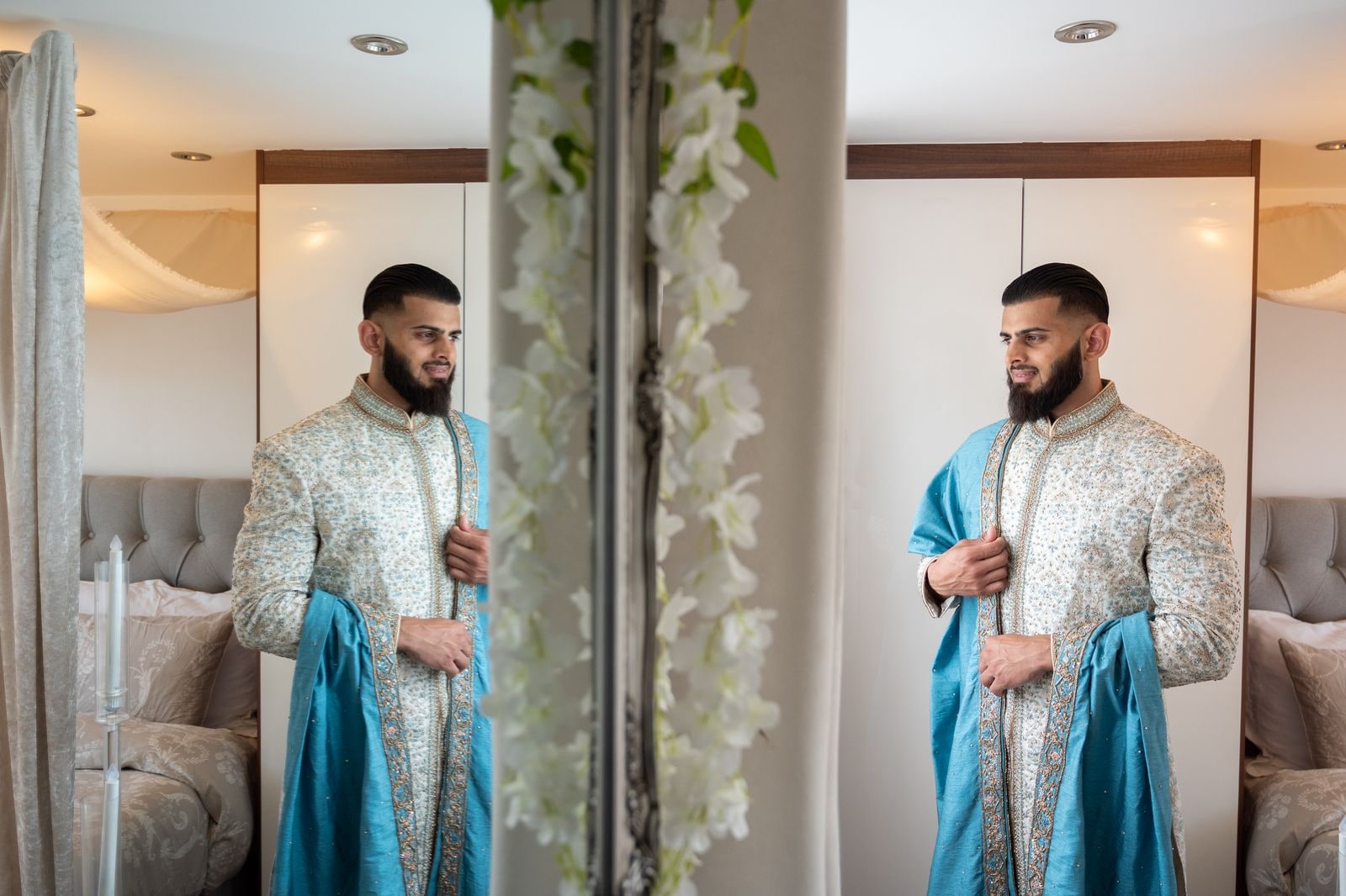 Groom checking his reflection in the mirror in his sherwani and blue shawl
