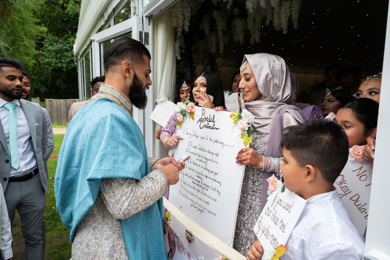 Groom reading the handwritten bridal contract the bride's family hold up to him