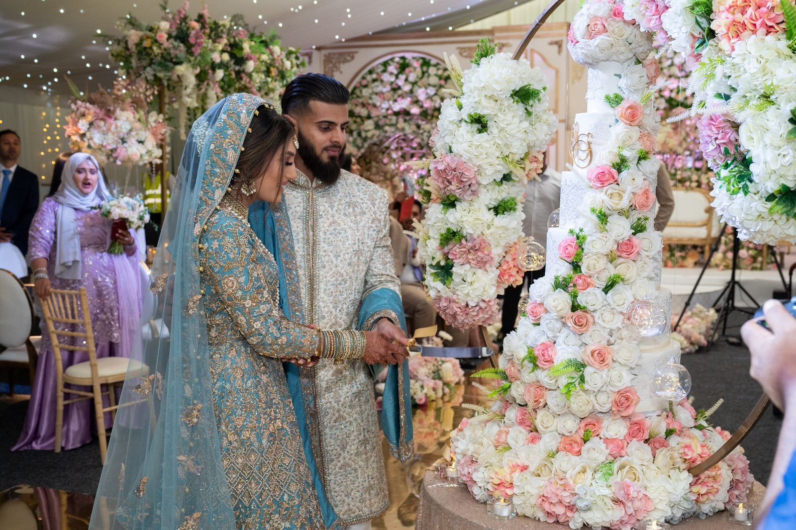 Bride and groom cutting the tall flowered cake together