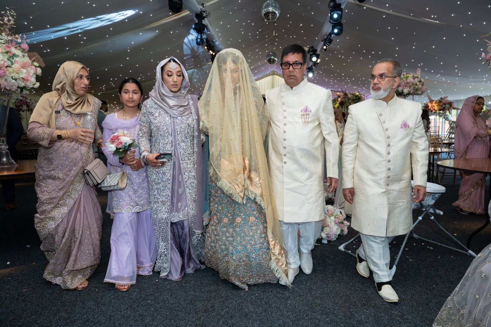 The bride walked in under her veil by her father, family alongside