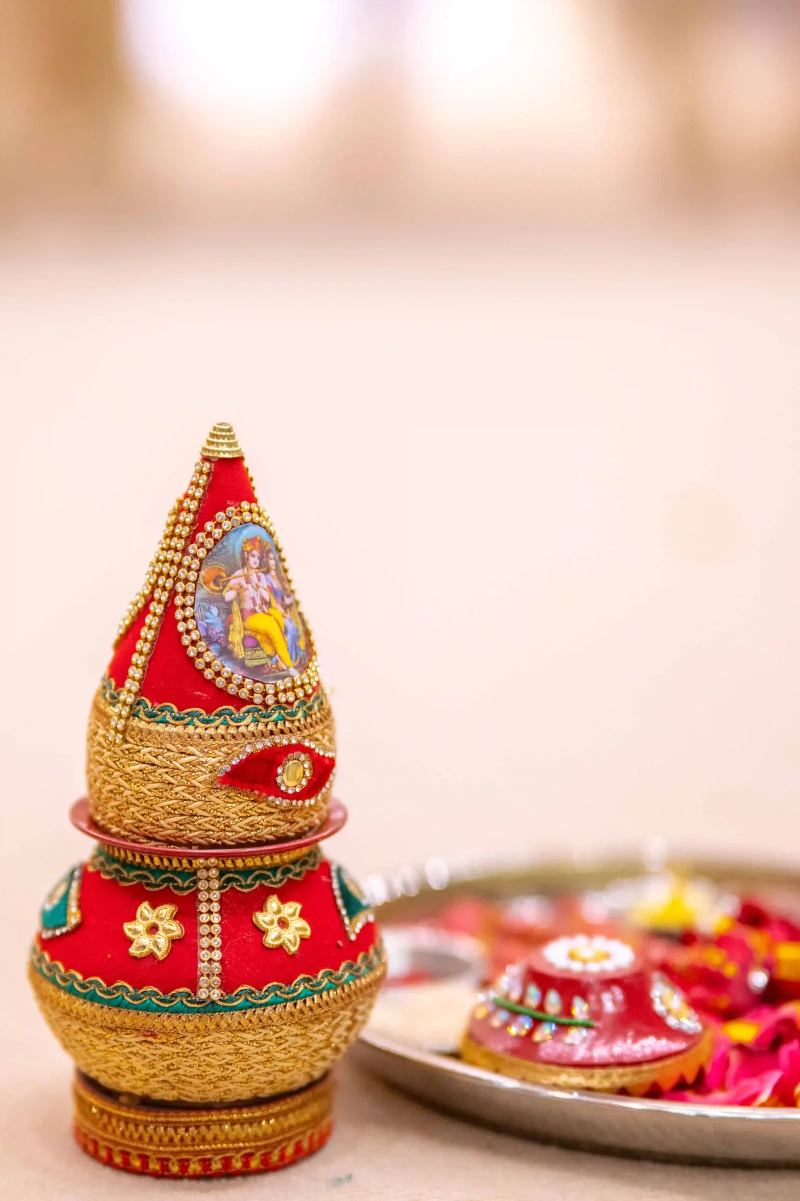 A decorated red and gold kalash on a tray, set out for the ceremony