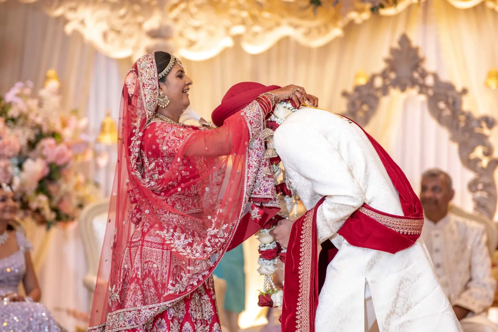 Bride placing the flower garland over her groom's red turban