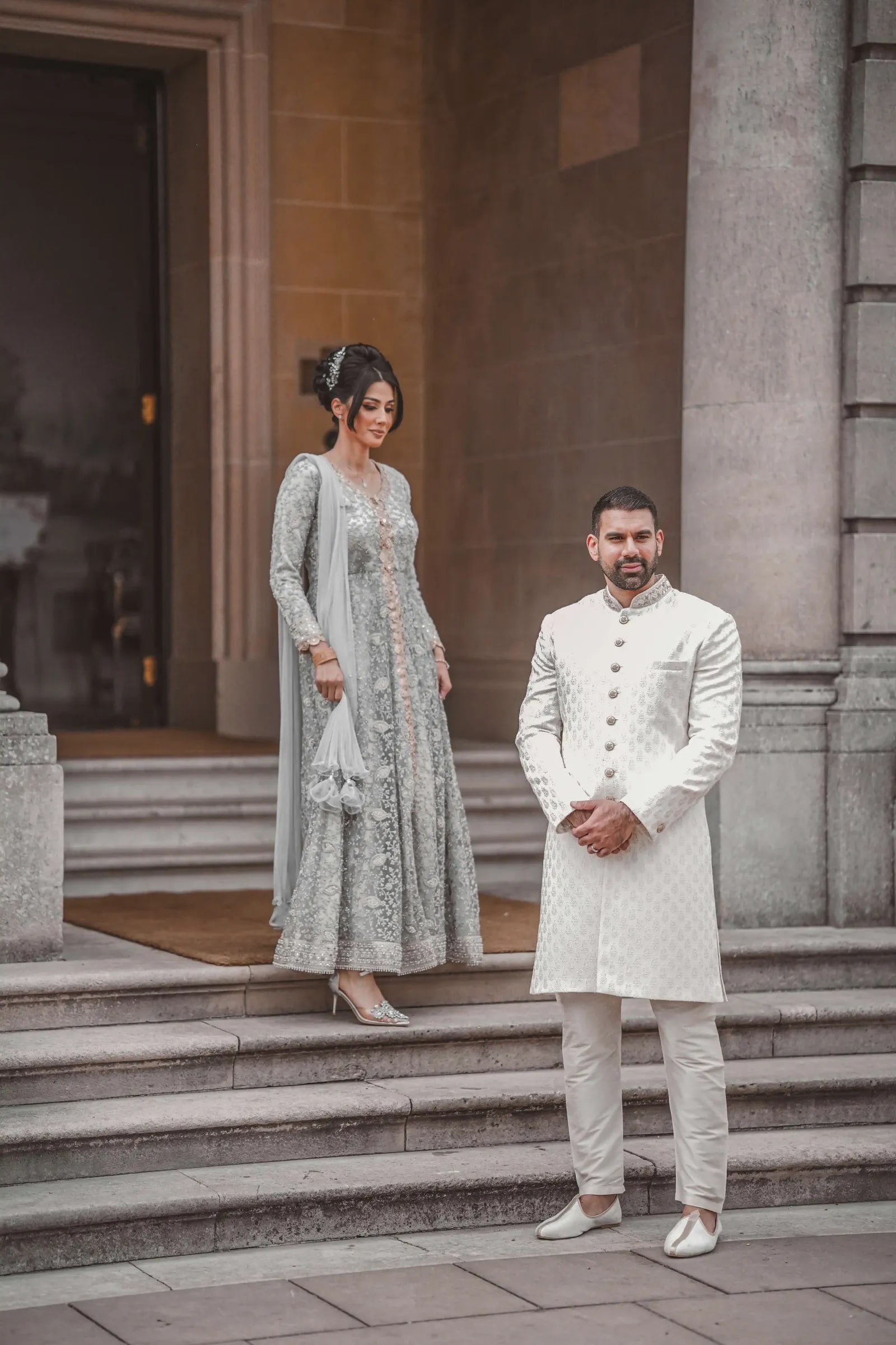 Bride and groom standing apart on the stone steps between the columns