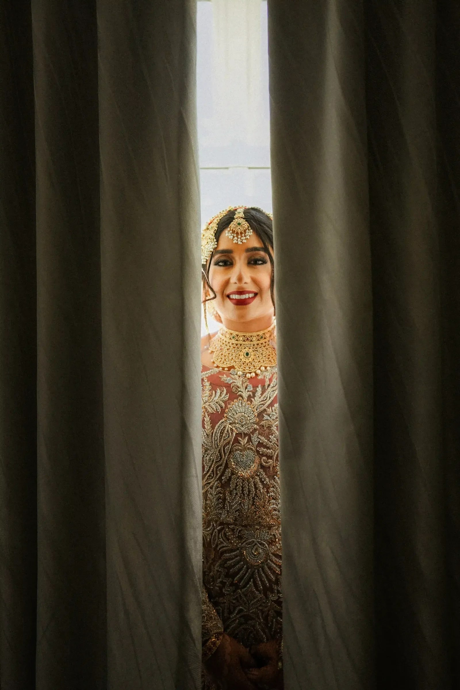 Bride glimpsed through a gap in a dark curtain before she comes out